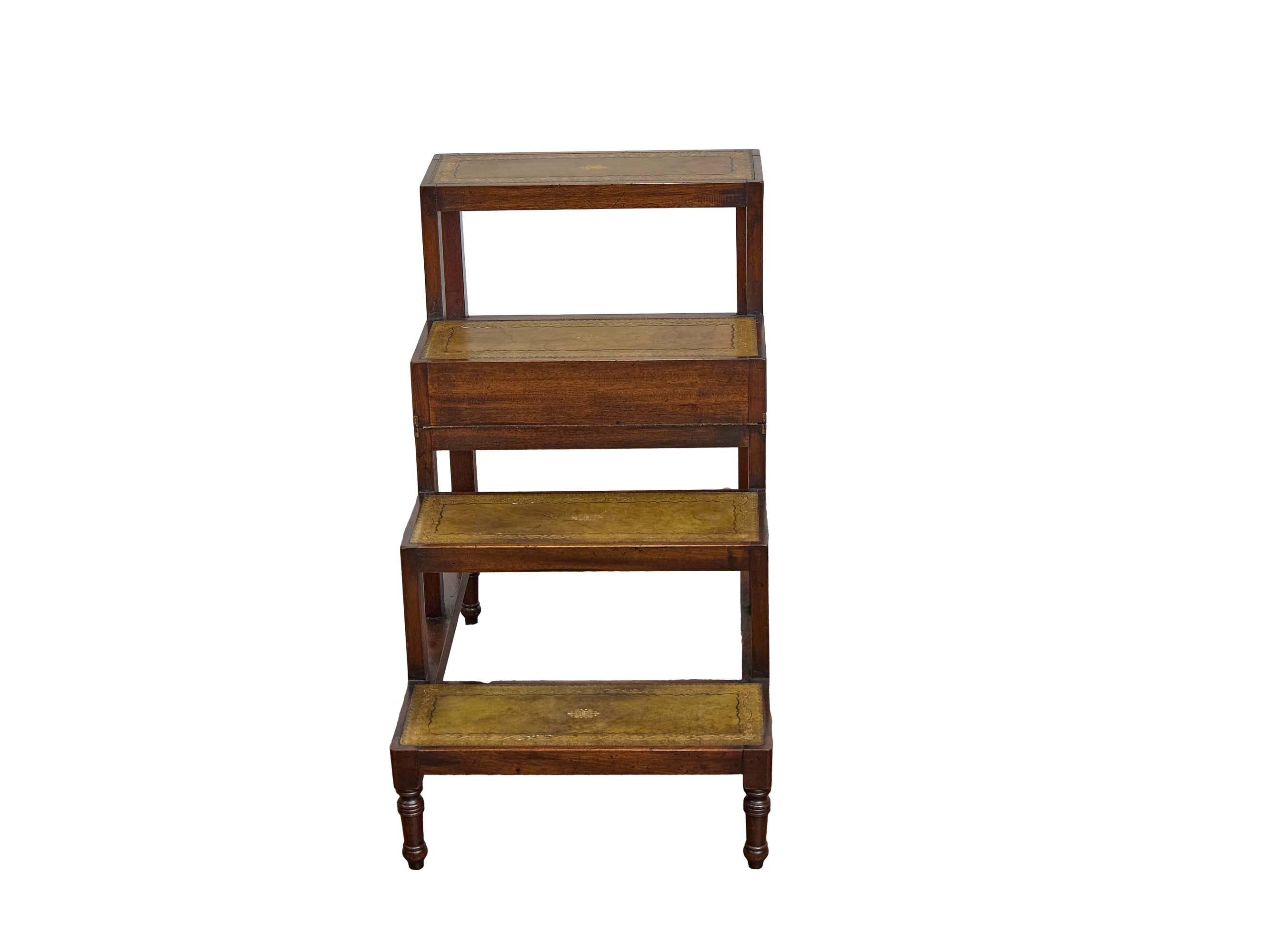 Un raffinato set di gradini da biblioteca inglesi del XIX secolo in mogano, sapientemente progettati per combinare eleganza e praticità. I quattro gradini graduali sono inseriti in pannelli di pelle verde lavorata, ciascuno decorato con bordi dorati