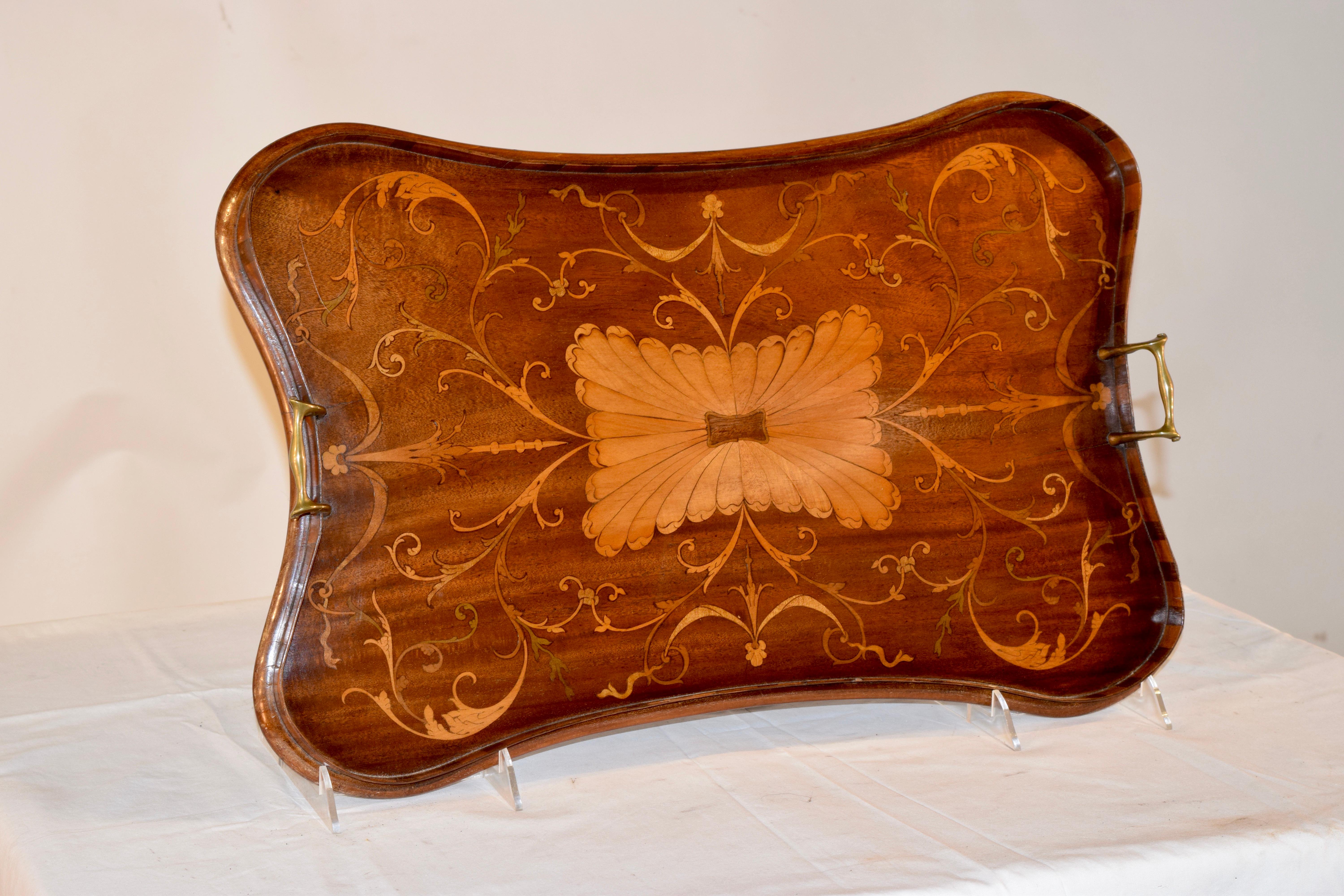 19th century mahogany shaped serving tray with serpentine and inlaid molded gallery and bulbous brass handles. The tray has a central satinwood feathered design, and intricately inlaid satinwood design depicting vines, leaves and bellflowers, early