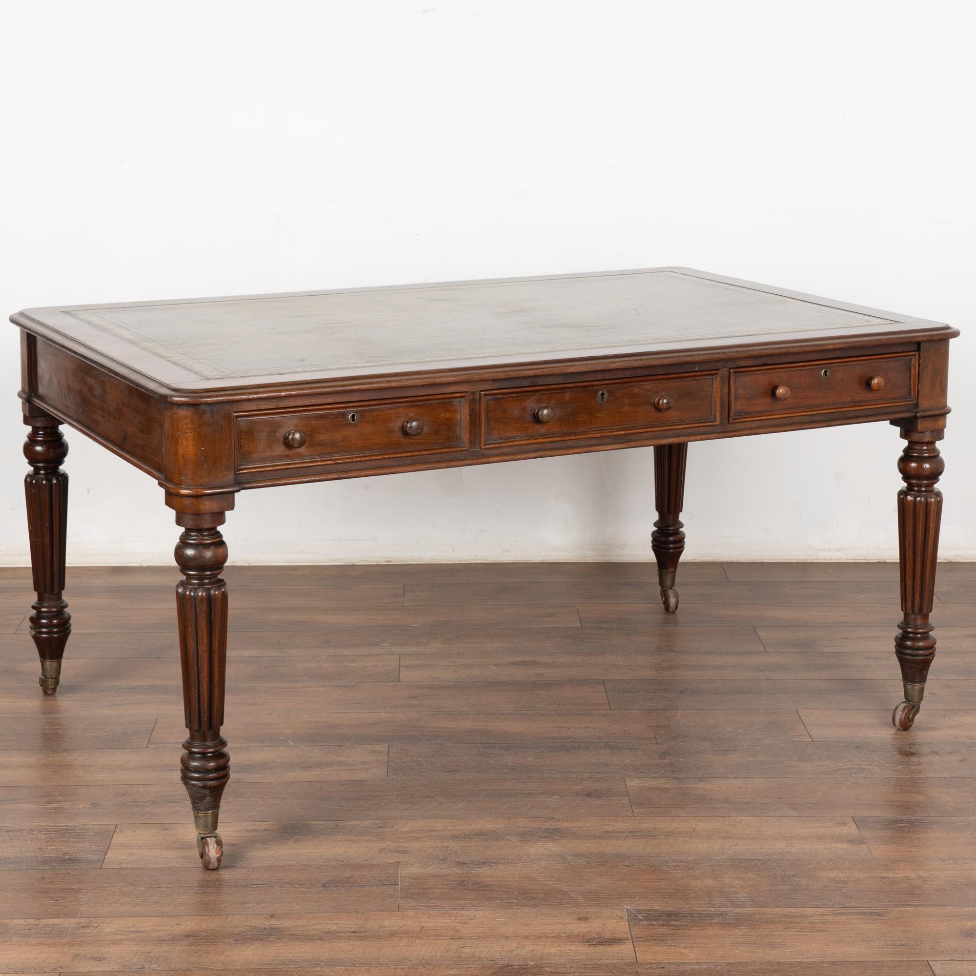 Distinctive and timeless, this English mahogany partners desk has three functioning drawers on each side, lovely turned legs resting on castors.
Please review photos of the aged green/olive leather top, which reveals generations of use. Scratches,