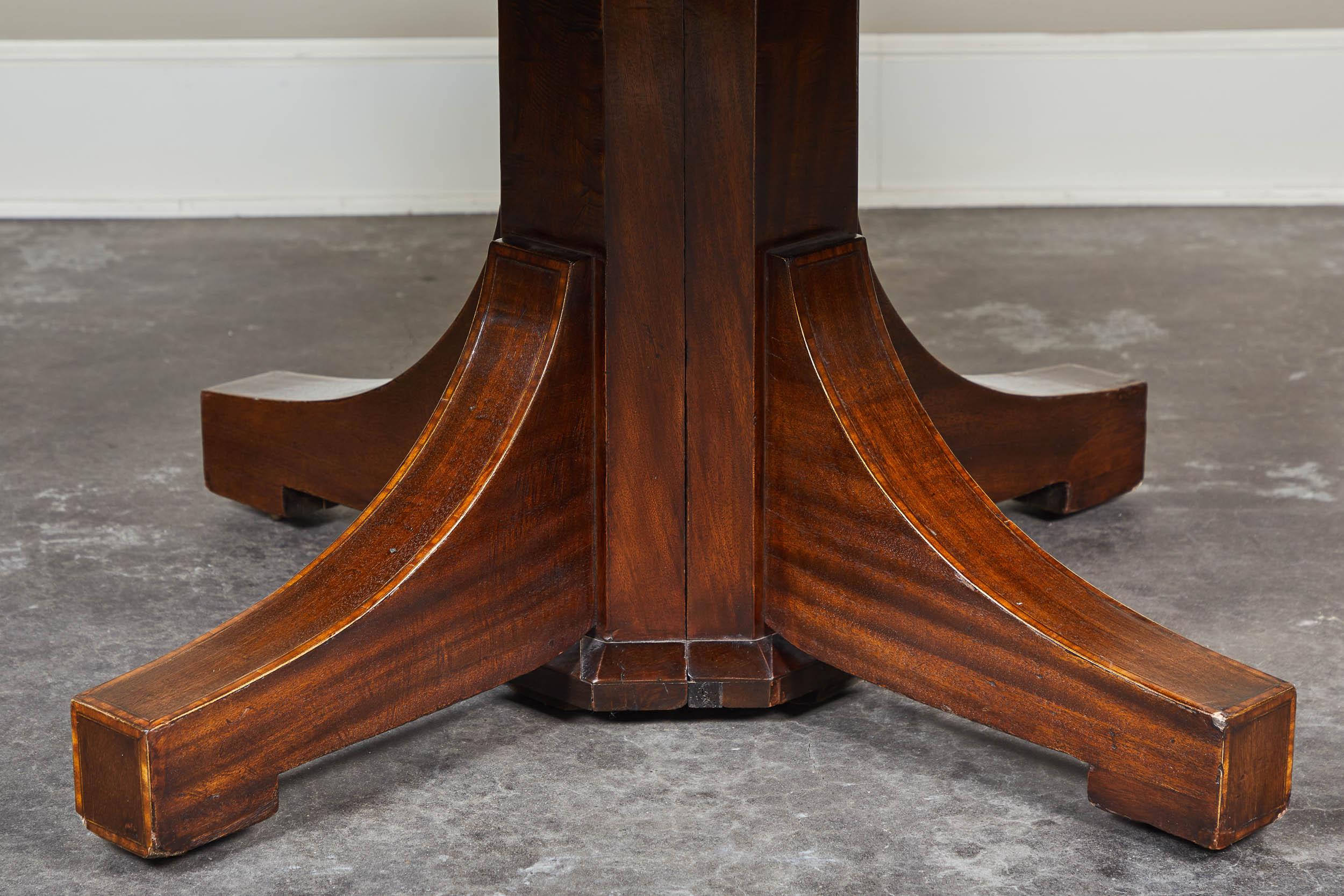 A 19th century English mahogany pedestal table. Features two leaves and an inlaid banding on top and legs. Simple, clean design while still allowing for extended seating with a leaf. Could easily fit into most breakfast nooks without the leaf,