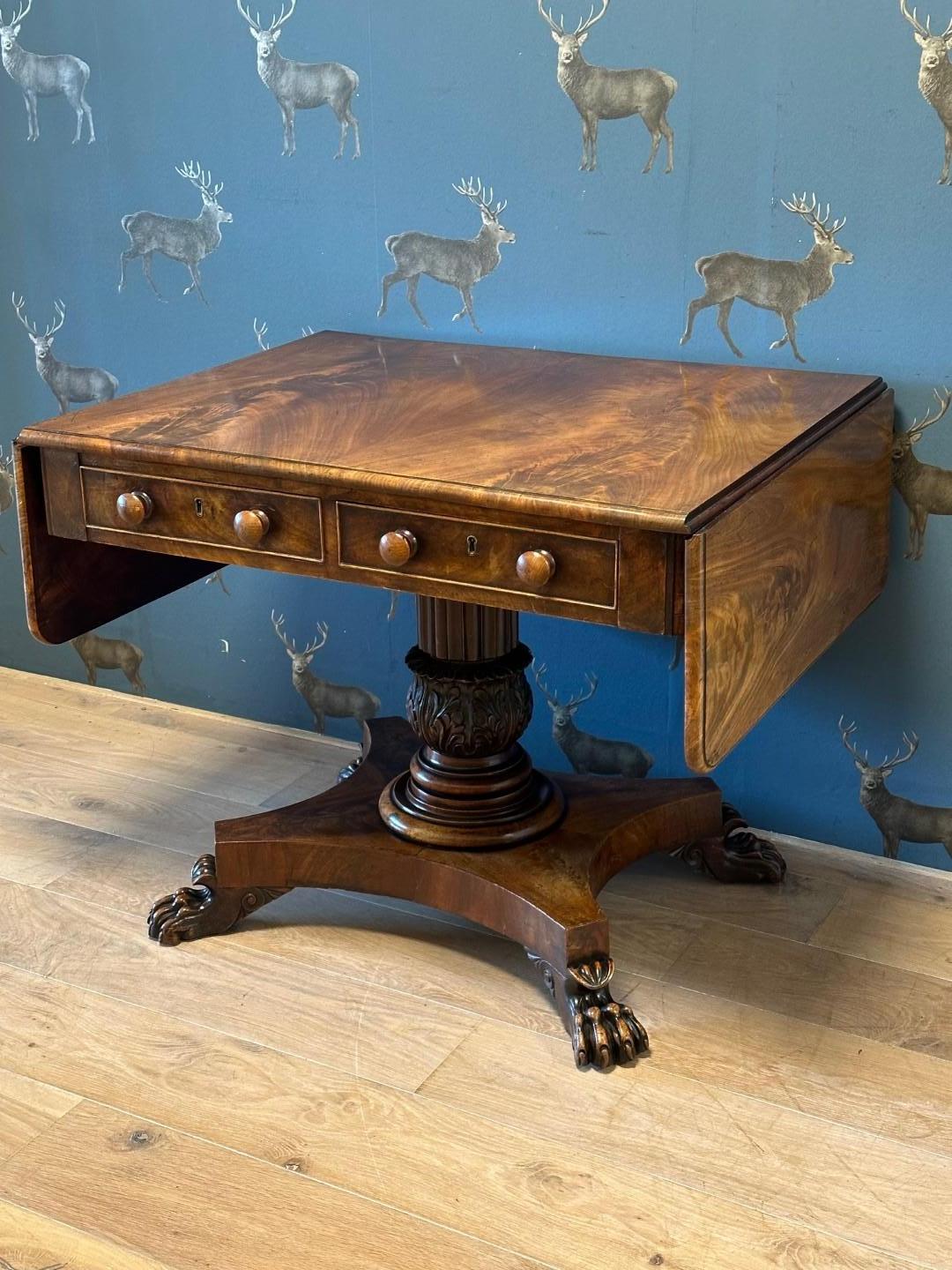 Impressive English mahogany sofa table. The table has a beautiful patina. Two drawers at the front and 2 drawer fronts at the back (no drawers). The table has 2 fold-out leaves on both sides. The table has a beautiful flower mahogany top. The column