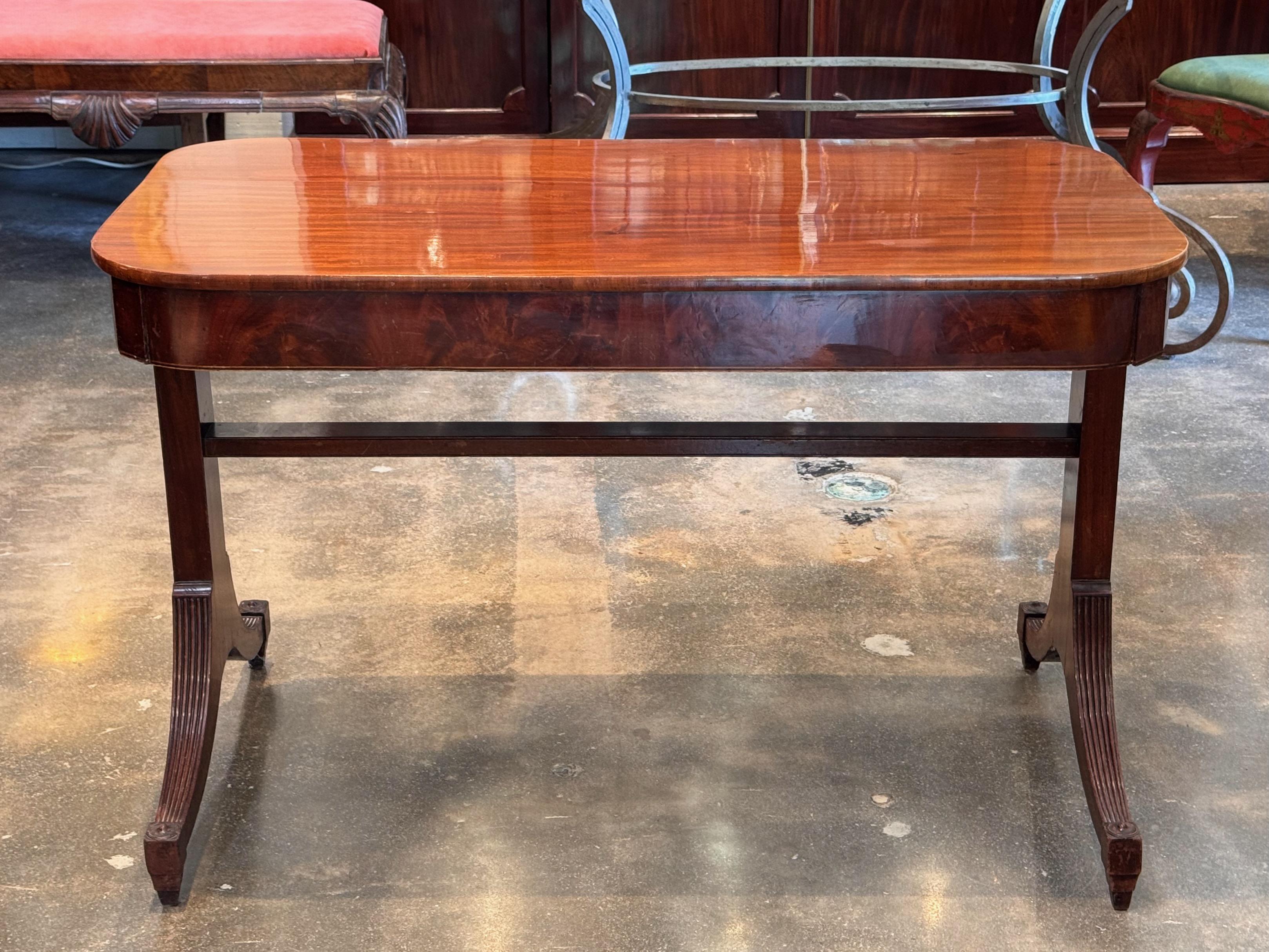 Table de canapé anglaise classique du 19e siècle avec un riche plateau en acajou et des pieds évasés finement effilés se terminant par des pieds cannelés. Le plateau façonné est soutenu par une base étirée, offrant à la fois élégance et stabilité.