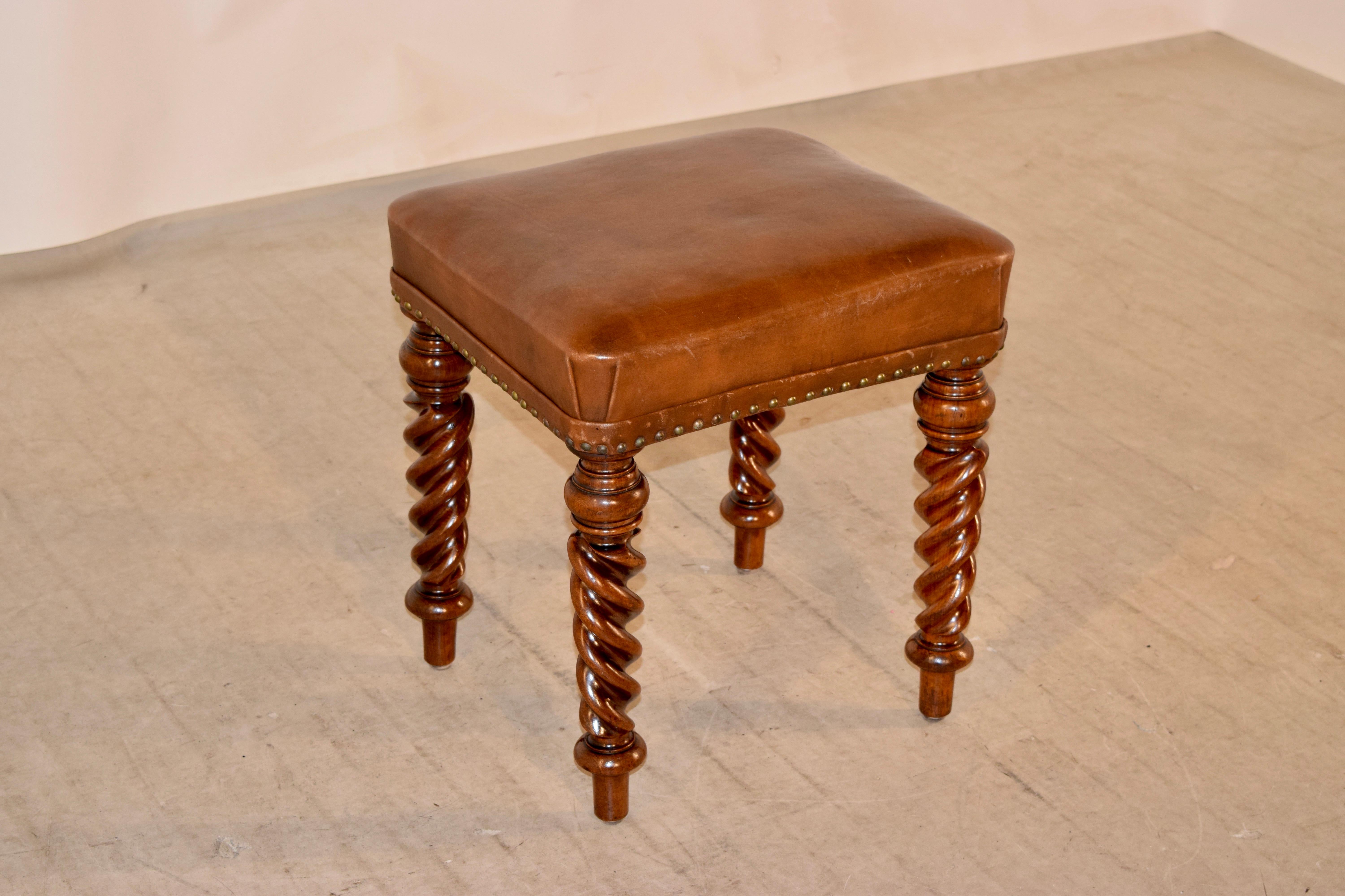 19th century English stool made from mahogany with a leather upholstered seat, which has brass nail decoration around the base of the seat. The legs are hand-turned and are a wonderful flame twist shape.