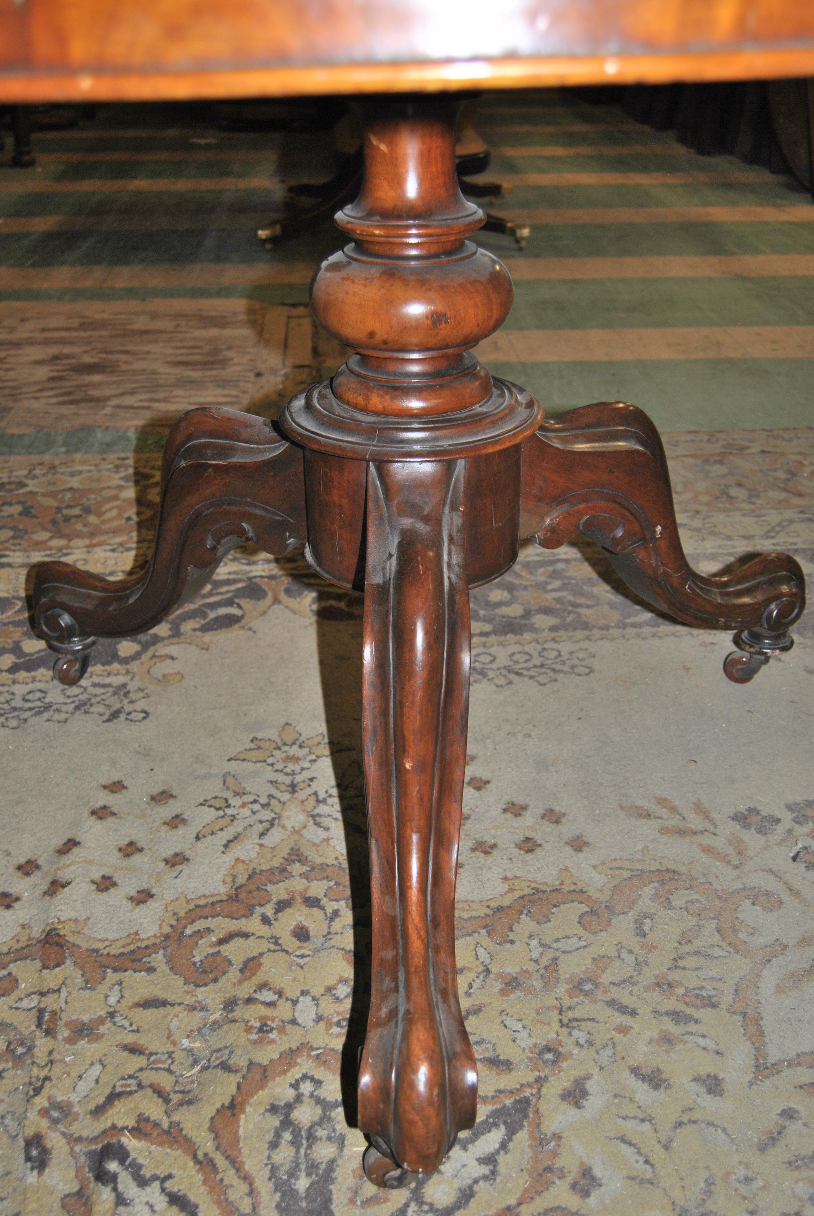 This is a solid mahogany tilt-top table made in England, circa 1860. The round top is a highly figured mahogany with a nicely molded edge. The top sits on a nicely turned pedestal that is supported by 3 carved and shaped down swept Queen Anne legs
