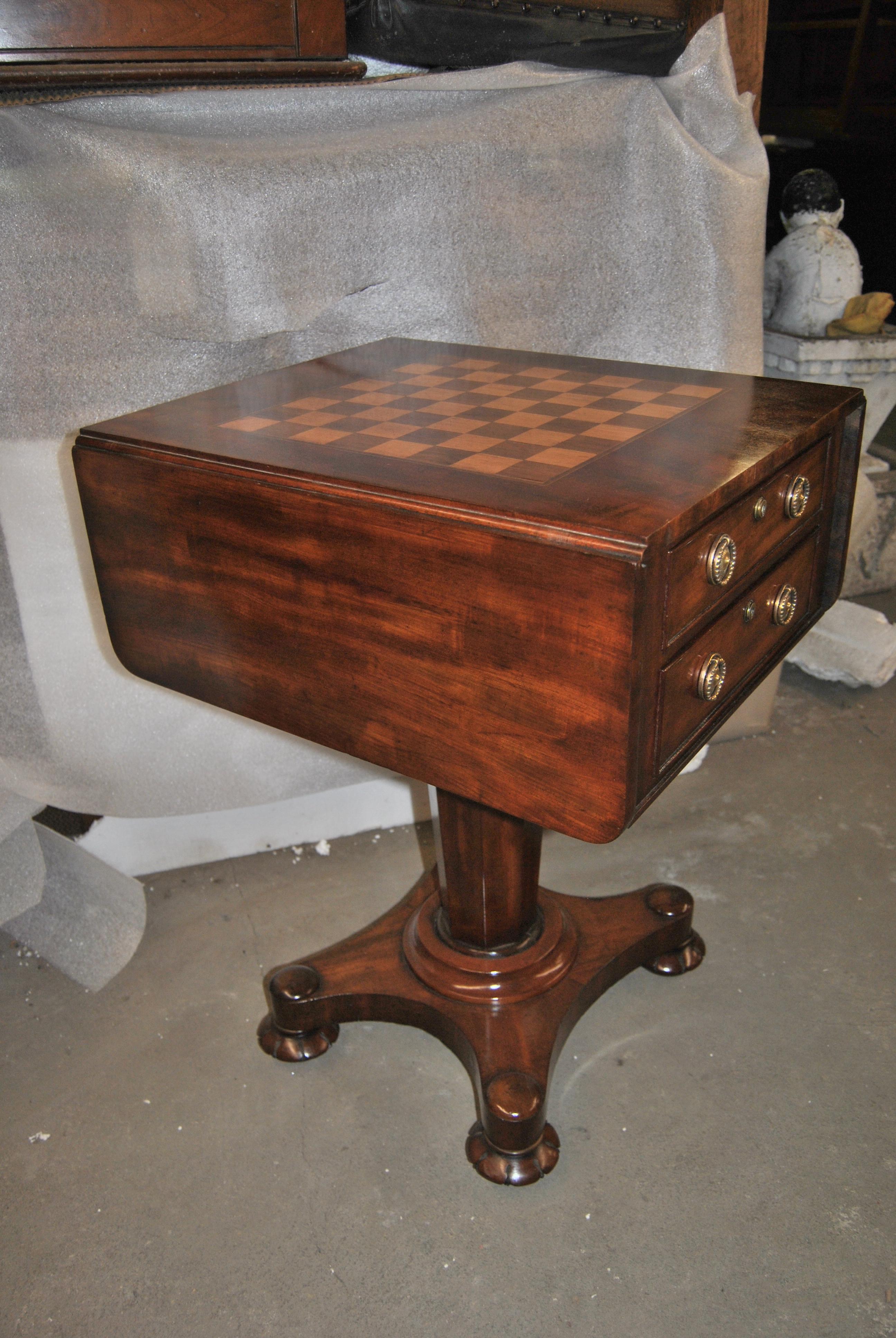 This is a mahogany work table, side table, lamp table, game table, end table, Etc. that was made in England, circa 1850. The top of the table has a game board inlaid in satinwood and walnut with a Herringbone walnut banding around the game board.