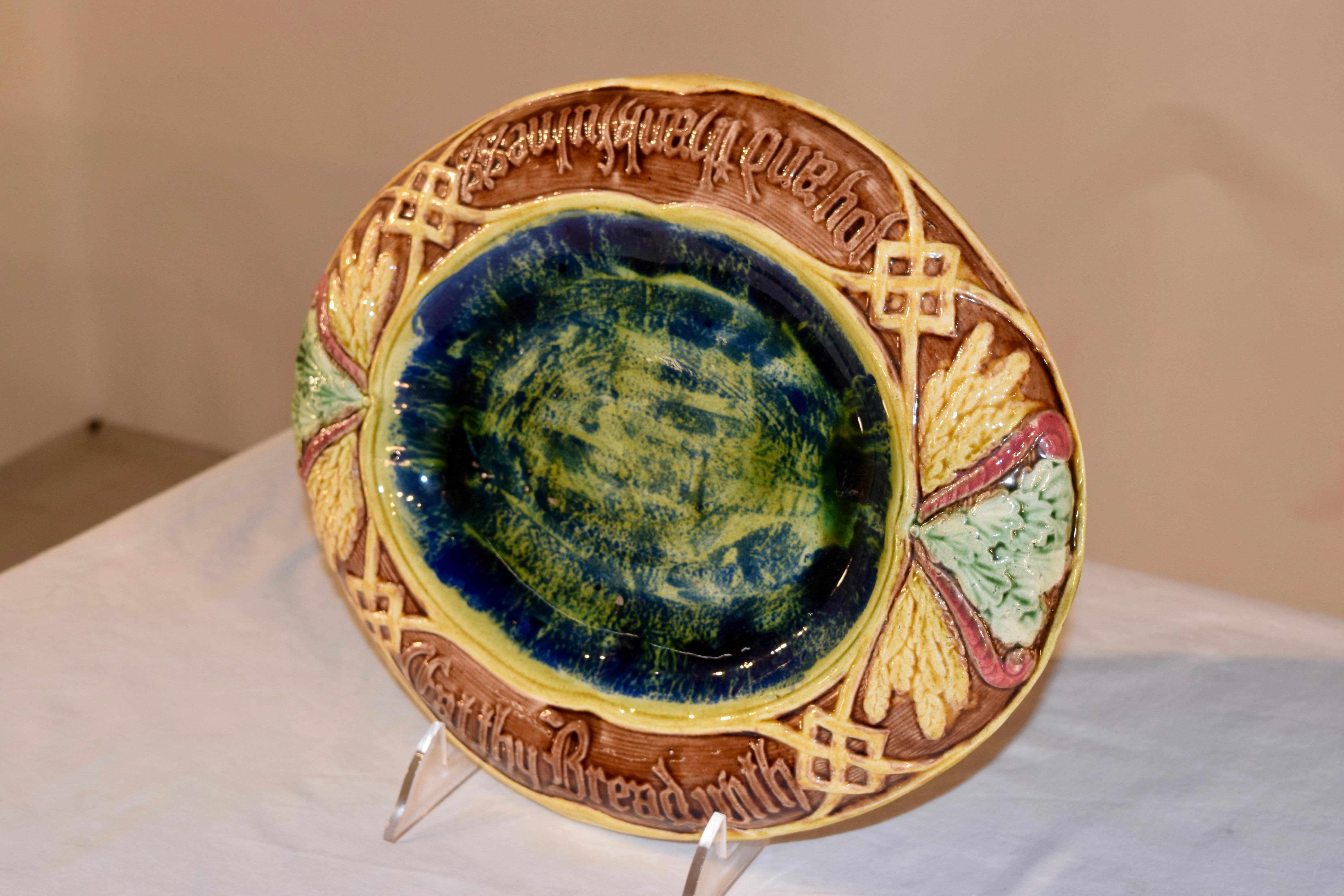 19th century majolica bread tray from England with a multi colored central medallion in blue and green, surrounded by a lovely molded border in yellow, pink, green and blue with designs of wheat and geometric designs encircling the words 