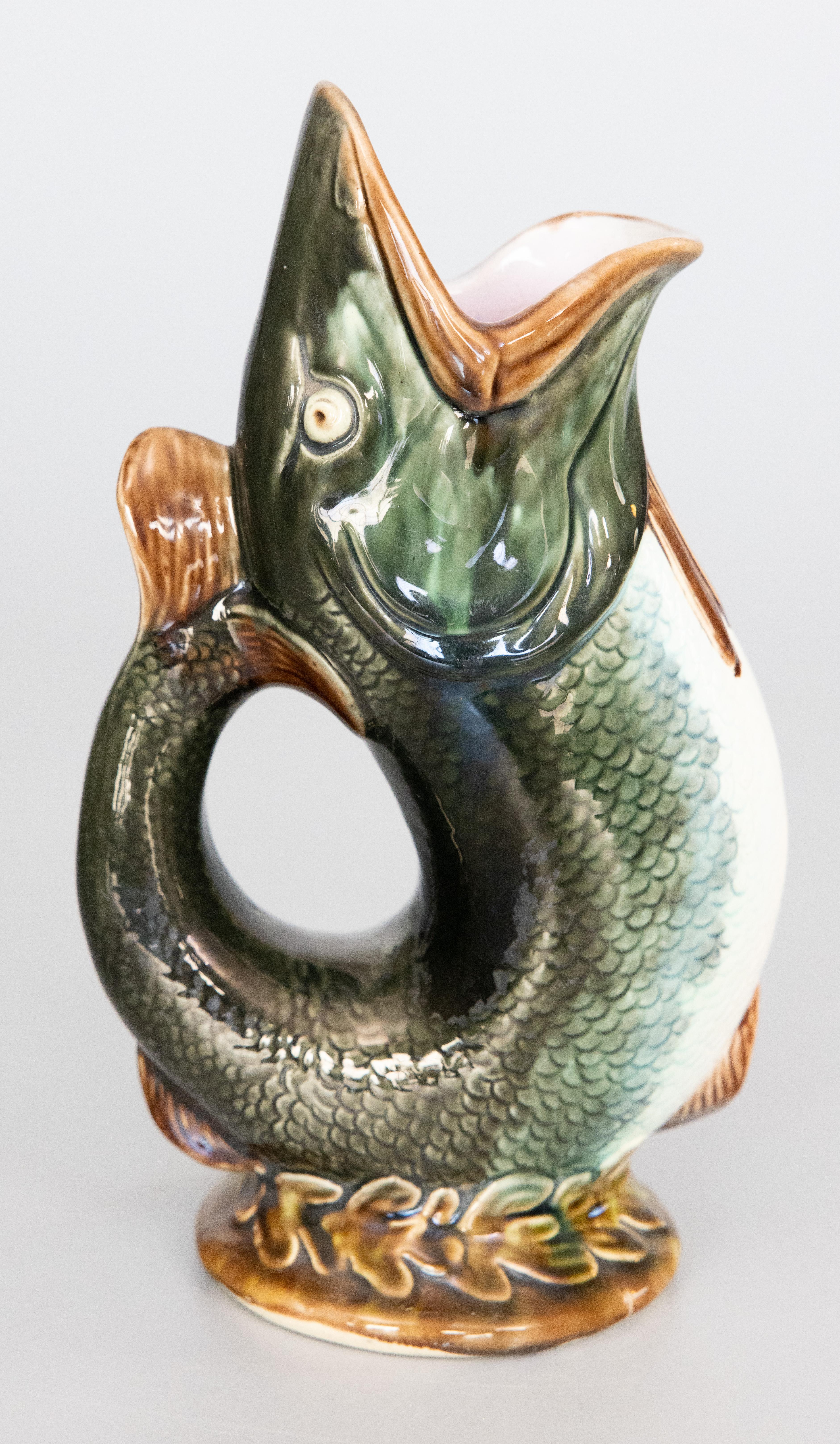A superb antique English majolica glazed ceramic gurgling fish pitcher or glug jug, circa 1880. Maker's mark on reverse. This whimsical fish pitcher has a stylish design in a lovely glazed dark green color with a decorative seaweed base, perfect for
