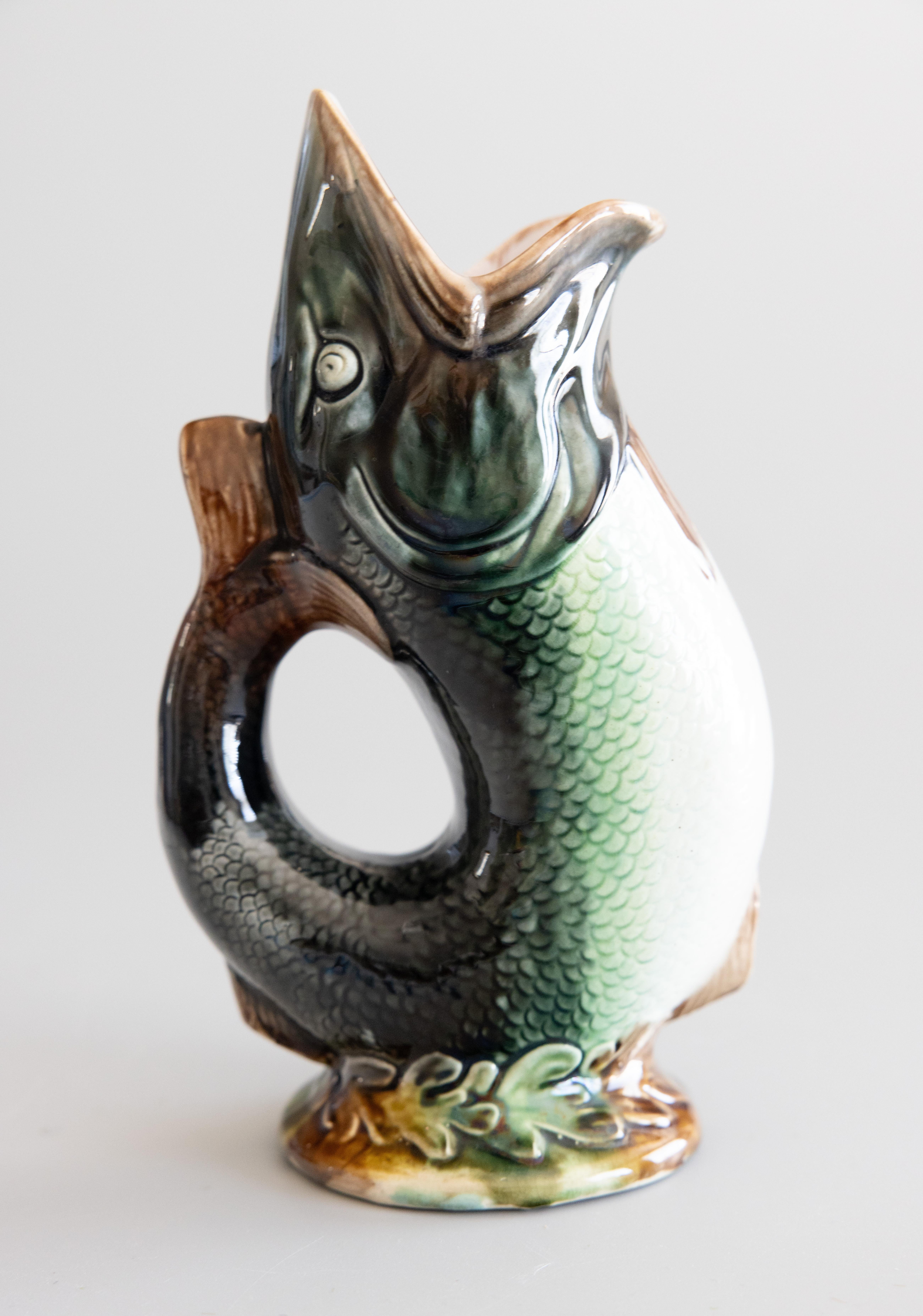 A superb antique English majolica glazed ceramic gurgling fish pitcher or glug jug, circa 1880. Maker's mark on reverse. This whimsical fish pitcher has a stylish design in a lovely glazed dark green color with a decorative seaweed base, perfect for