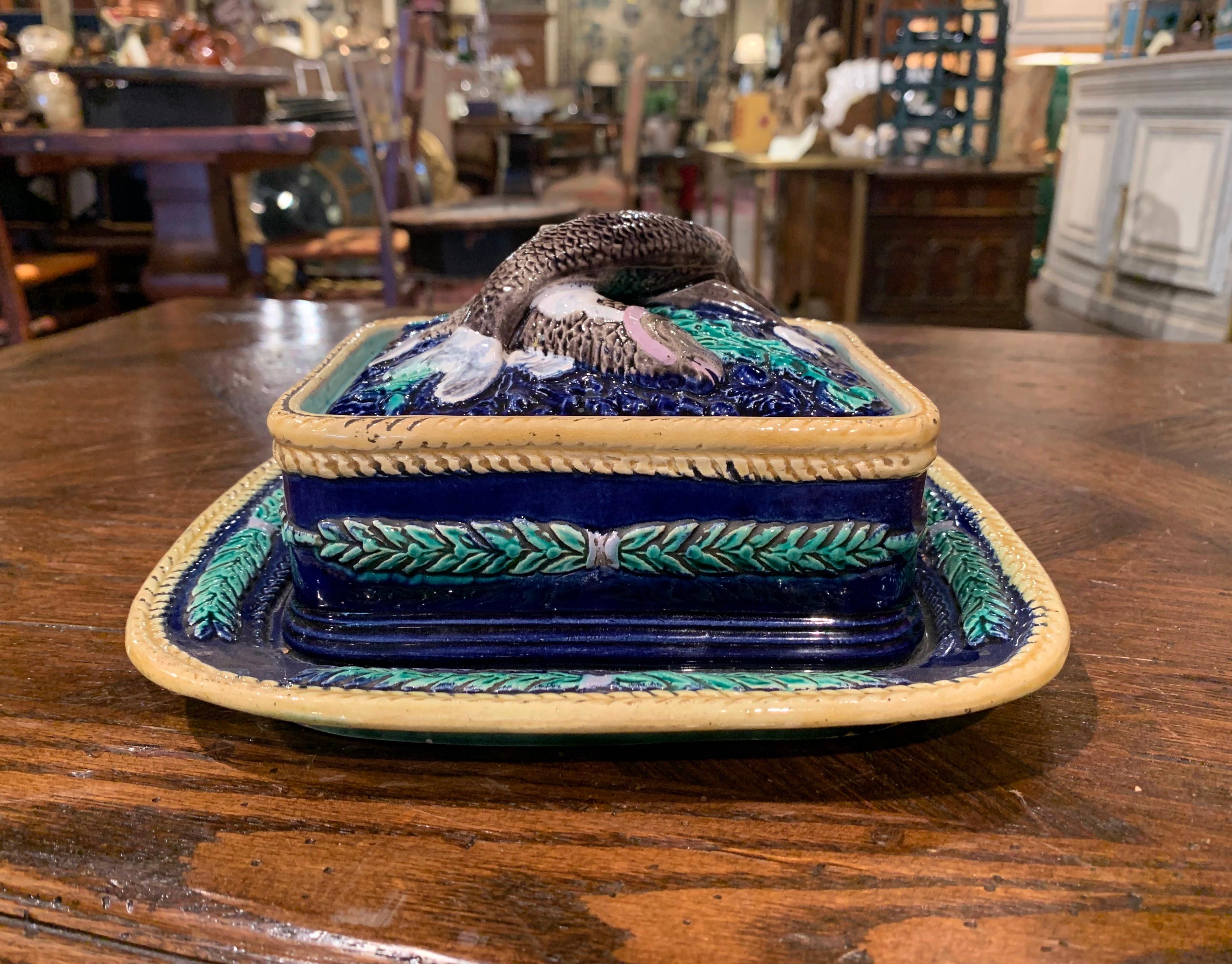 This colorful barbotine dish was created in England circa 1880; attributed to Georges Jones & Sons, the dish is rectangular in shape and sits on an attached platter base; it features high relief fish decor on seaweed ground on the removable top lid,