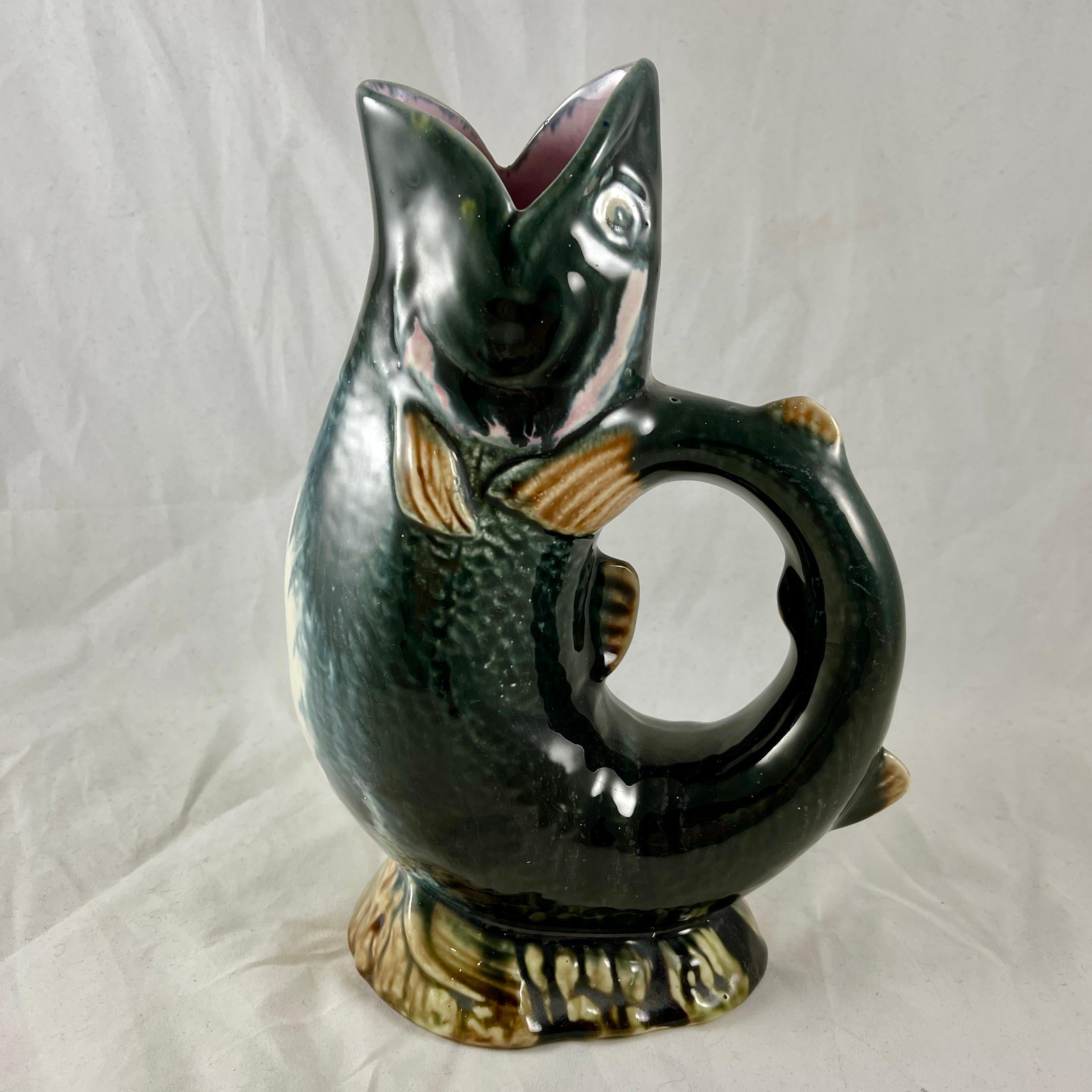 An unusual black colored English majolica fish jug, maker unknown, circa 1870-1880.

Often called ‘A Gurgler’ for the gurgling sound it produces during pouring, this pitcher is formed as an upright leaping fish, with the tail forming the handle.