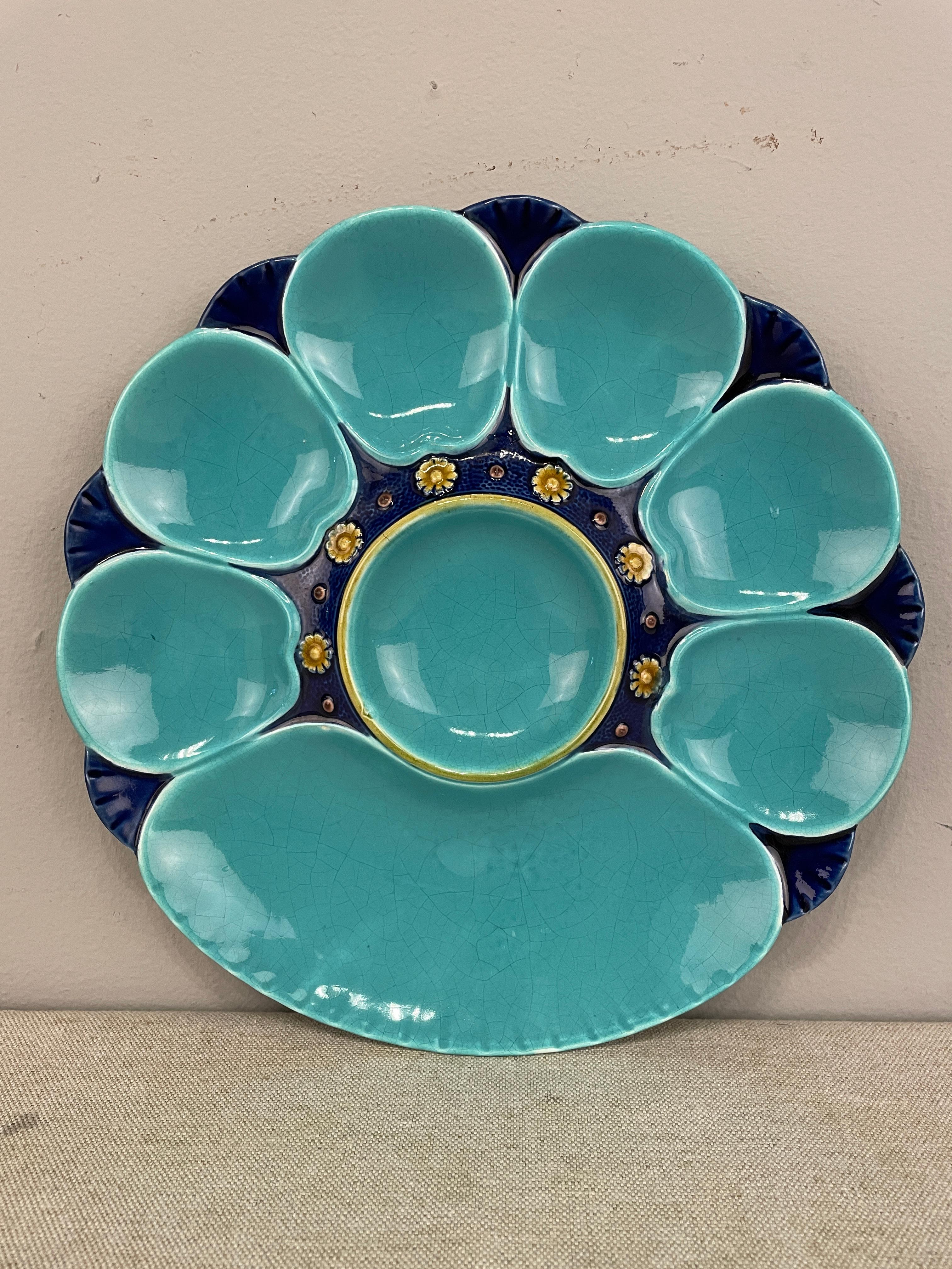 A good English Majolica plate, dated 1885 and marked Minton, with turquoise and cobalt blue oyster plate with a central well surrounded by small ochre flowers. Six small and one large shell shaped well around the rim.
Cobalt stipple ground with