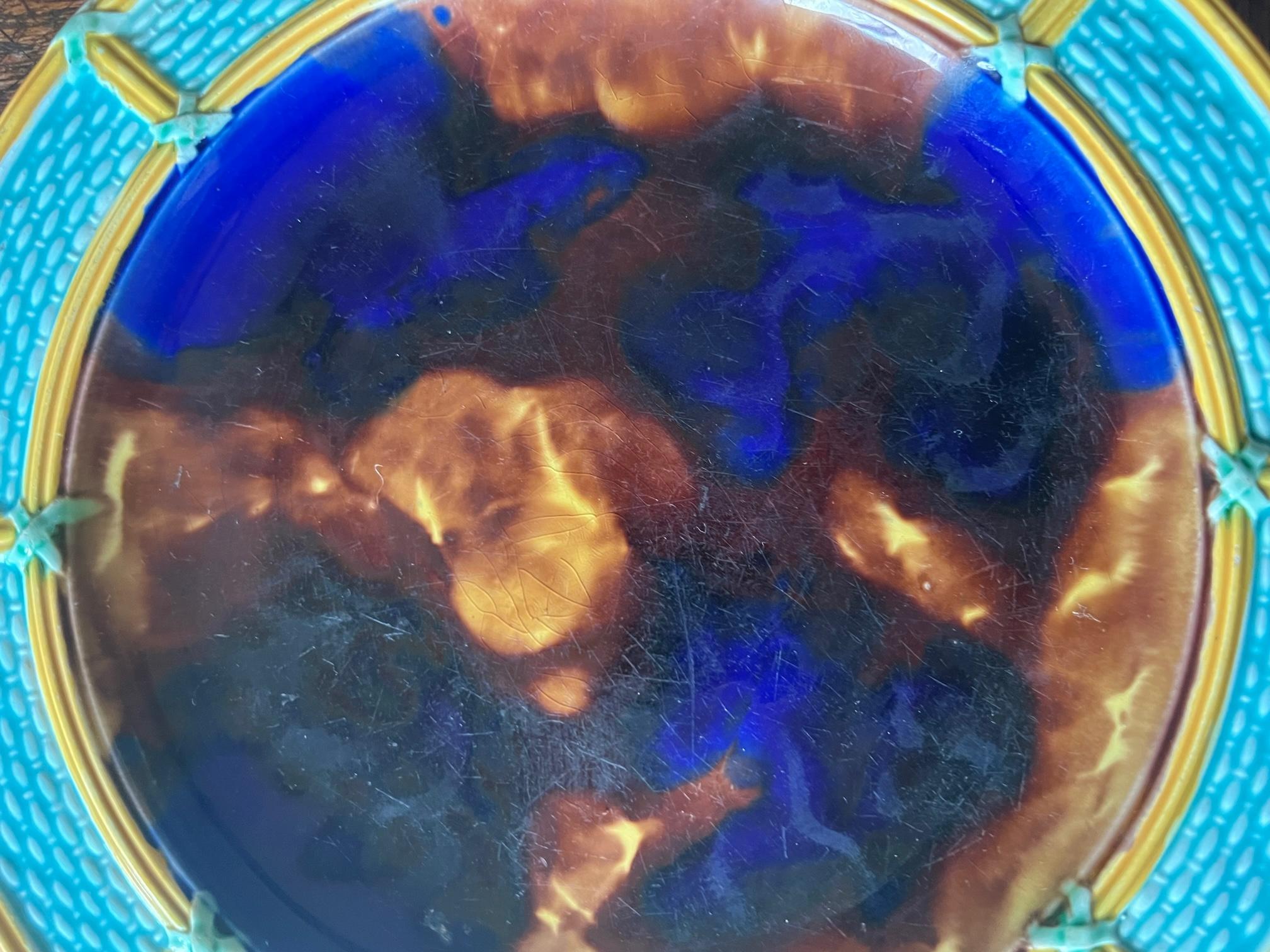 Assiette antique en majolique de Wedgwood décorée d'un bord en vannerie d'un turquoise vibrant et d'un centre en forme d'écaille de tortue bleue. L'assiette est frappée de l'empreinte Wedgwood et comprend la marque imprimée datant l'assiette de 1875.