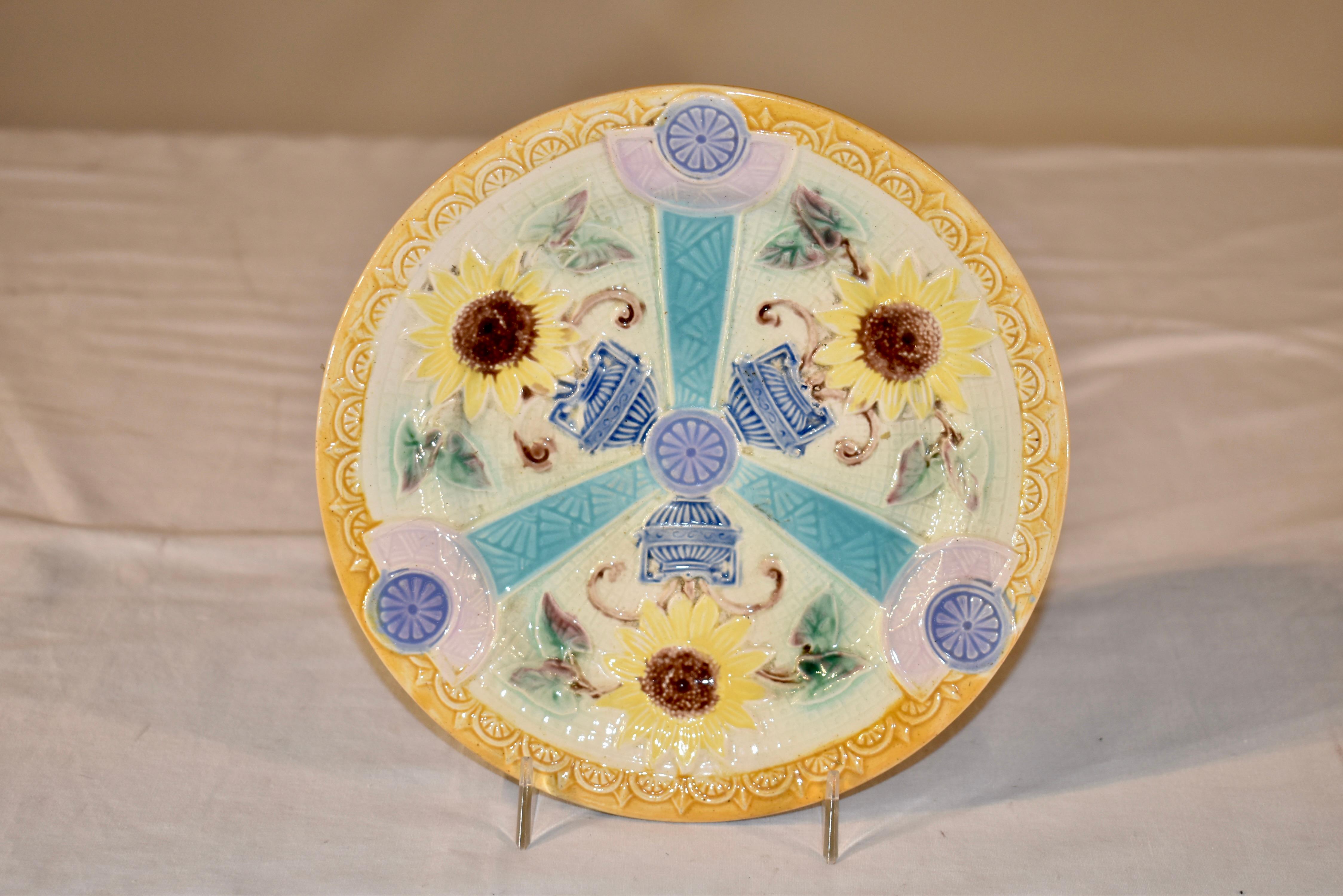 Assiette en majolique du 19e siècle provenant d'Angleterre.  La bordure est d'une belle couleur jaune et entoure trois urnes centrales avec des tournesols, séparées par des motifs de type art nouveau d'éventails et de motifs géométriques.  La plaque