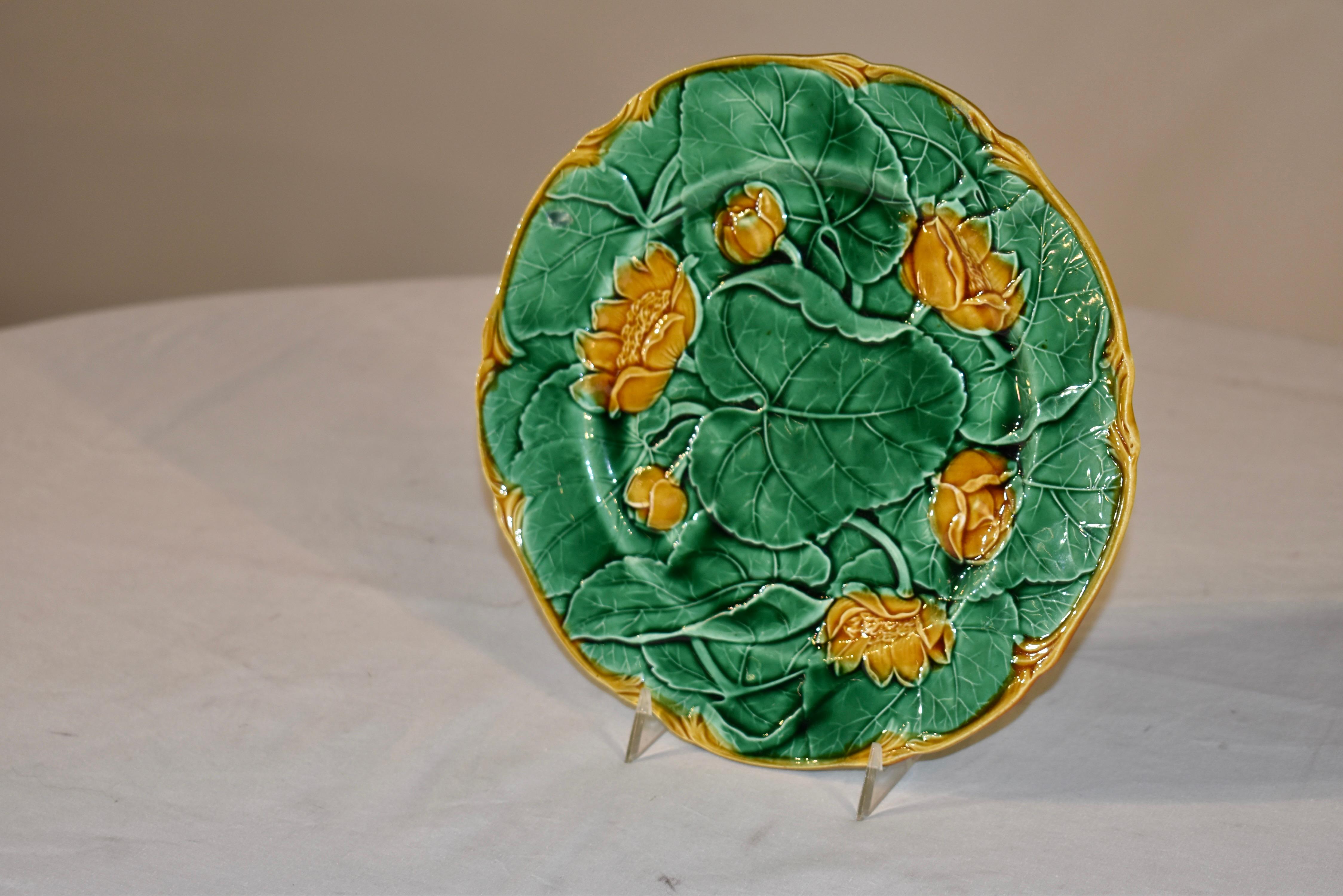 Assiette en majolique anglaise du 19e siècle avec un joli motif superposé de nénuphars et de feuilles.  Je n'ai jamais vu ce modèle auparavant - il est charmant.  La bordure est peinte en or, ce qui fait ressortir la couleur des nénuphars en