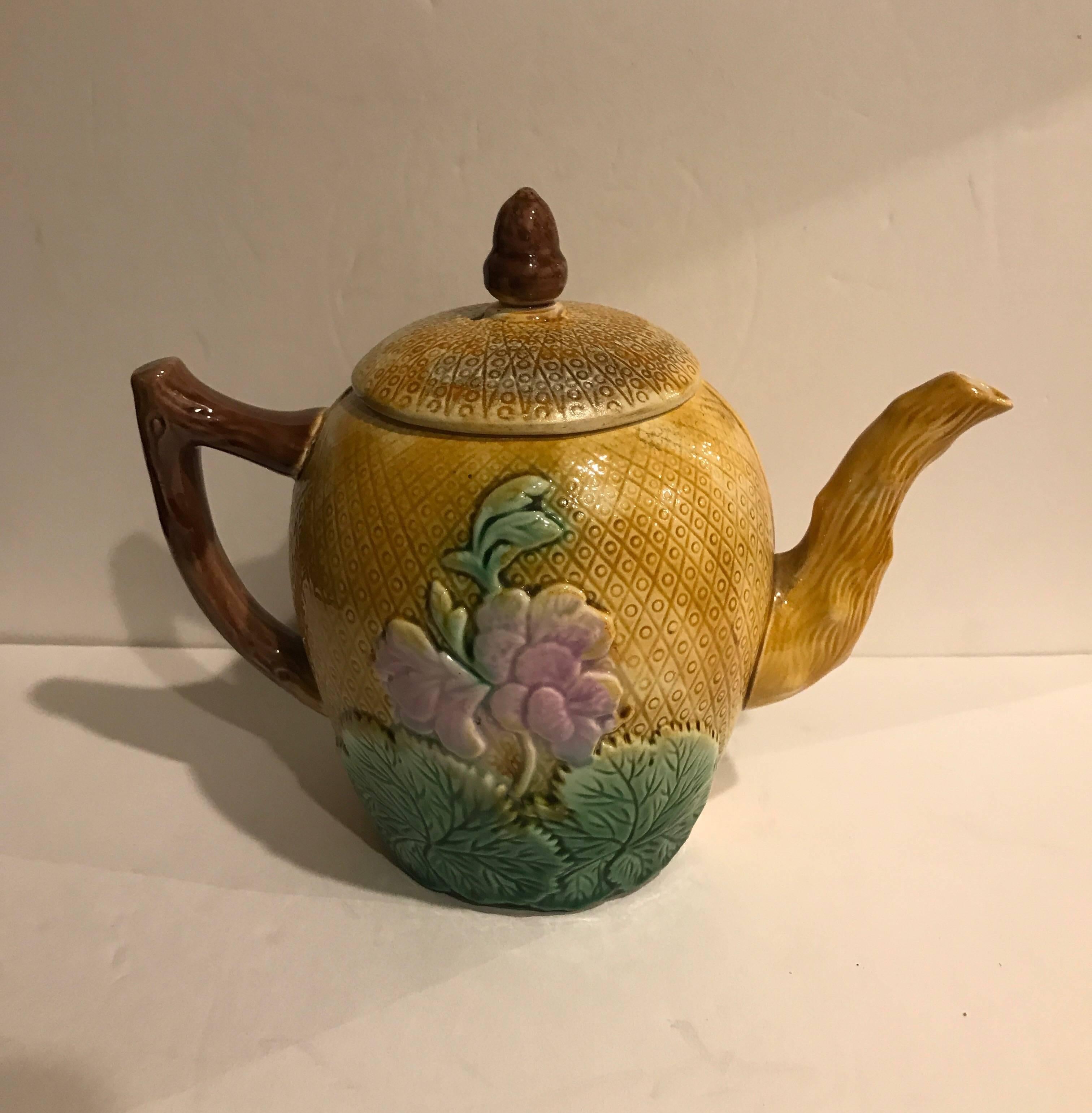 Vibrant and whimsical late 19th century Majolica teapot with yellow background. The geranium decoration on the front and back with acorn finial.