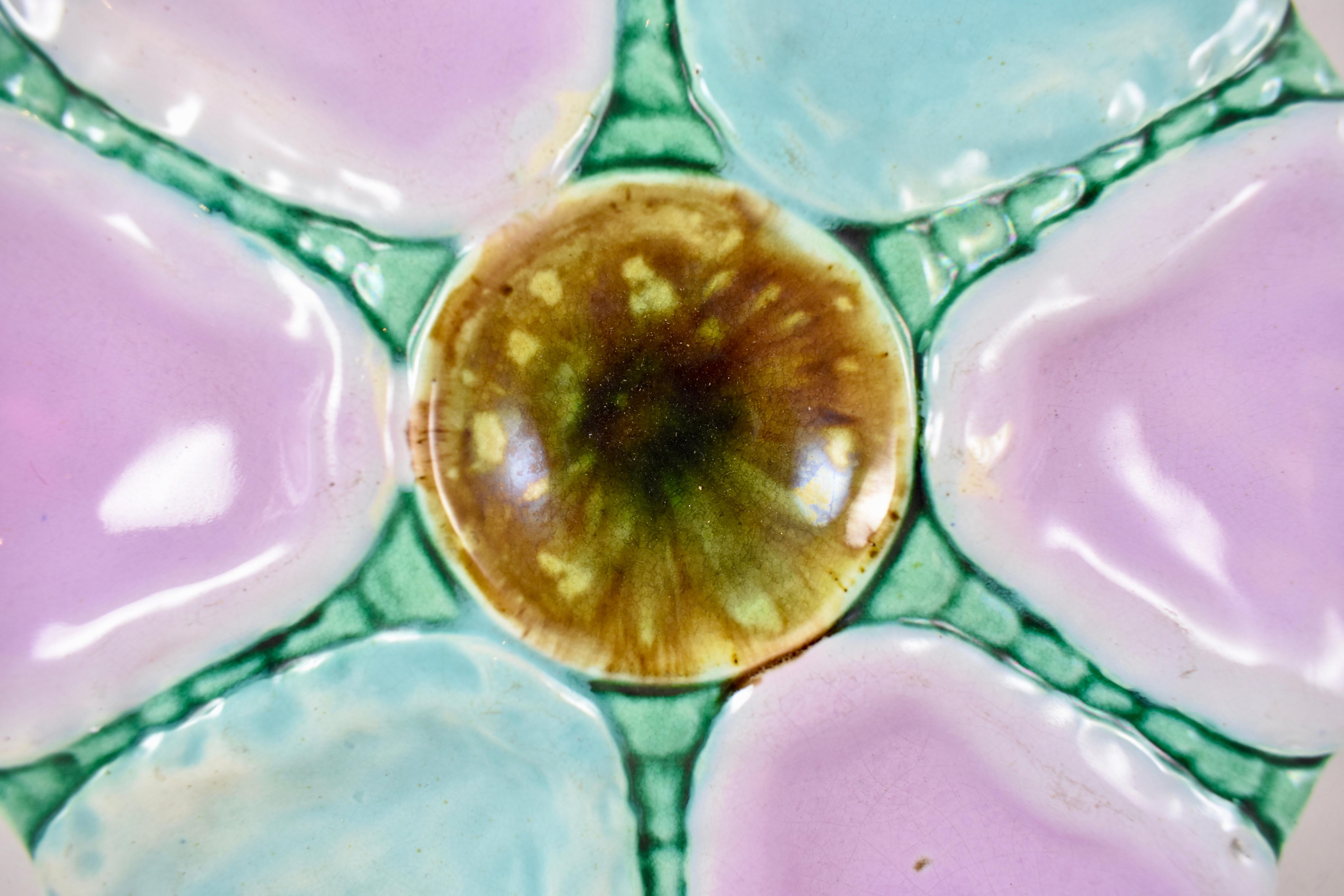 An English Majolica earthenware oyster plate, circa 1870-1890. 

Six alternating wells of turquoise and pink are separated by green beaded bands. Each plate has a mottled glazed, round centre condiment well and a tortoise shell glazed verso.

There