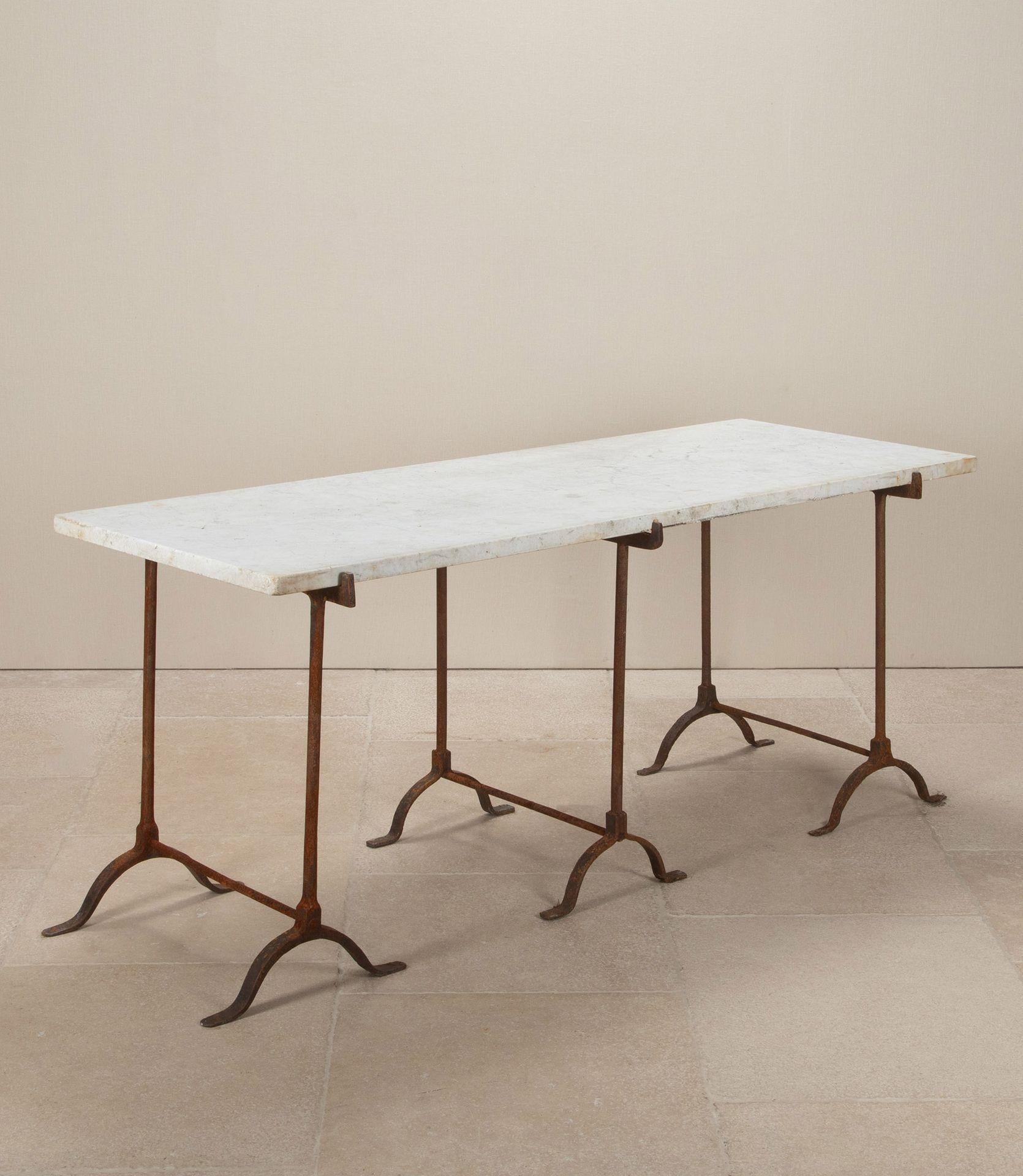 An impressive late 19th Century English marble table of simple construction.With a beautiful slab of Carrara marble supported by two hand-forged wrought iron trestles. A third trestle is available but not necessary. This table has many