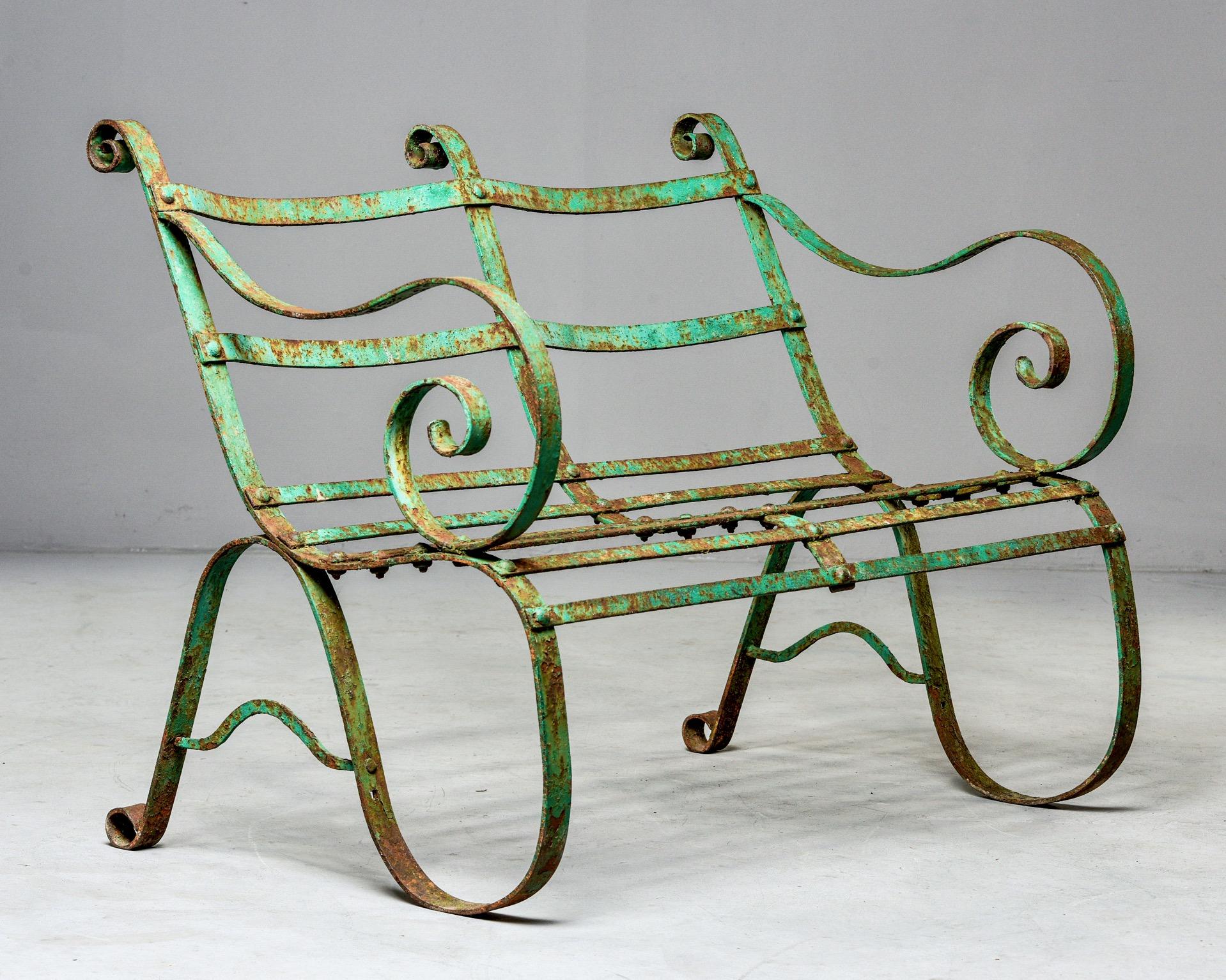 Early 19th century English two-seat garden bench features a curvy, metal frame and original green paint. Unknown maker.
Measures: Seat height 16”, seat width 38.25”
Seat depth 16.5”, arm height 27.25”.