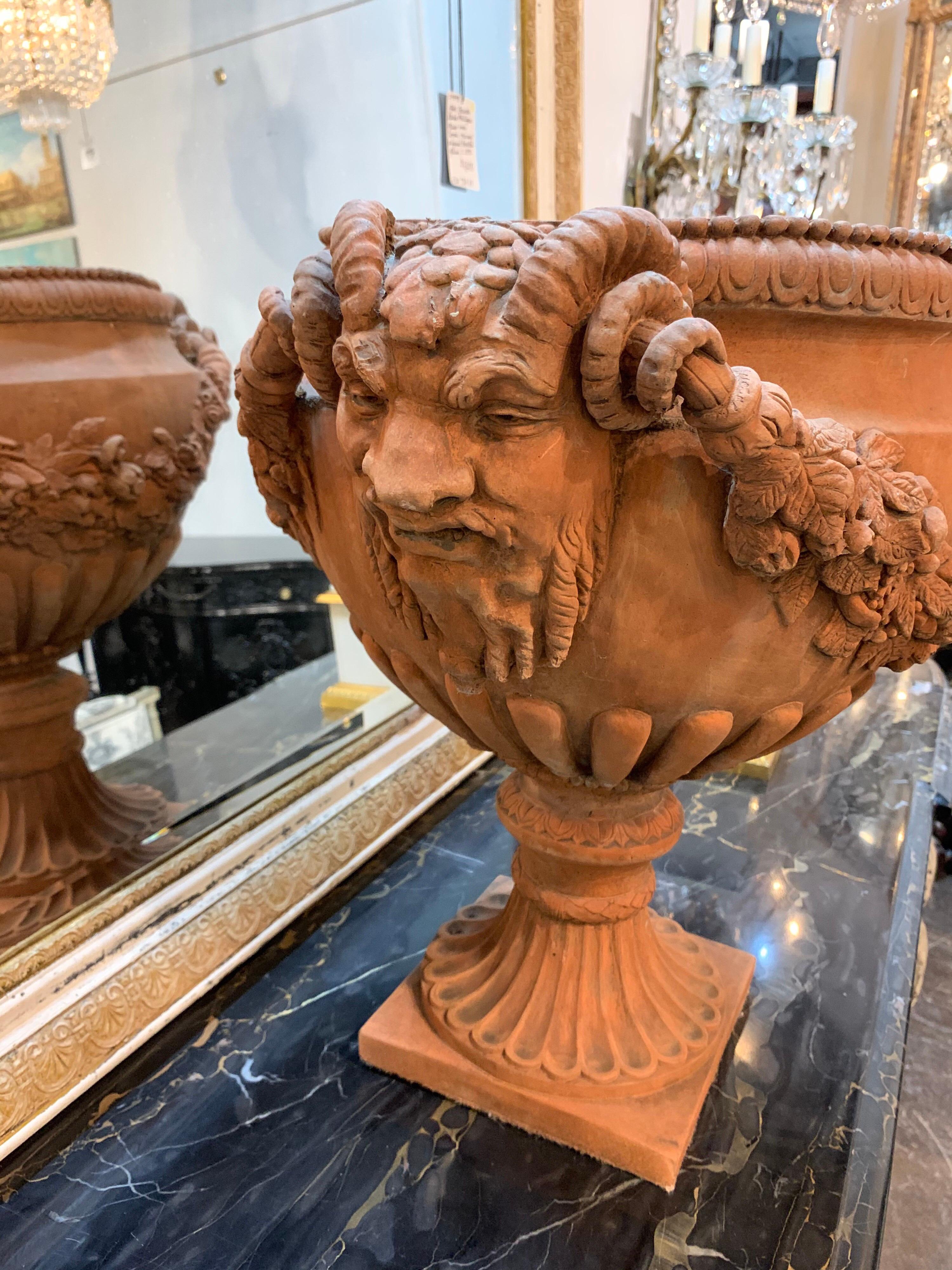 Lovely neoclassical style terracotta colored planter. This piece has floral details and an imposing face on the sides. So unique!