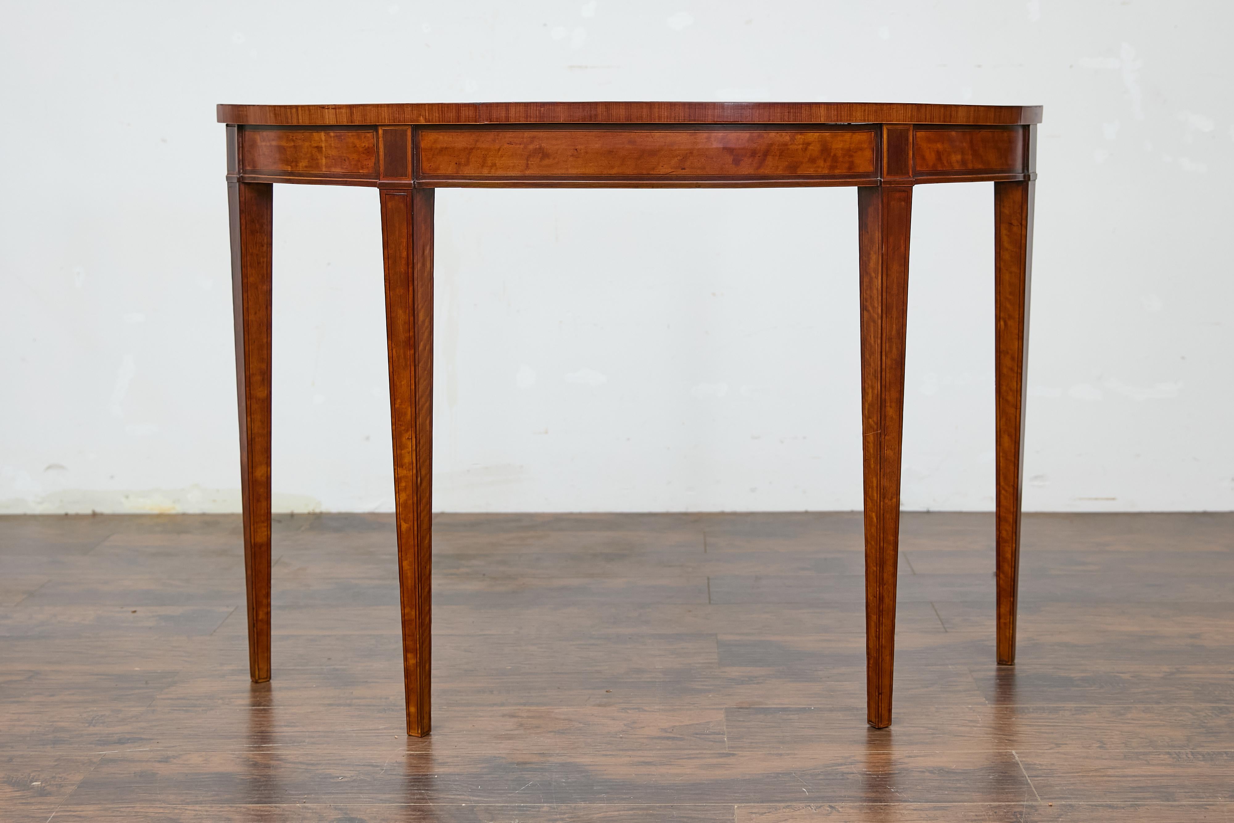 An English Neoclassical walnut demi-lune console table from the 19th century with tapered legs. This English Neoclassical walnut demi-lune console table from the 19th century captures attention with its elegant silhouette and rich walnut veneer. The
