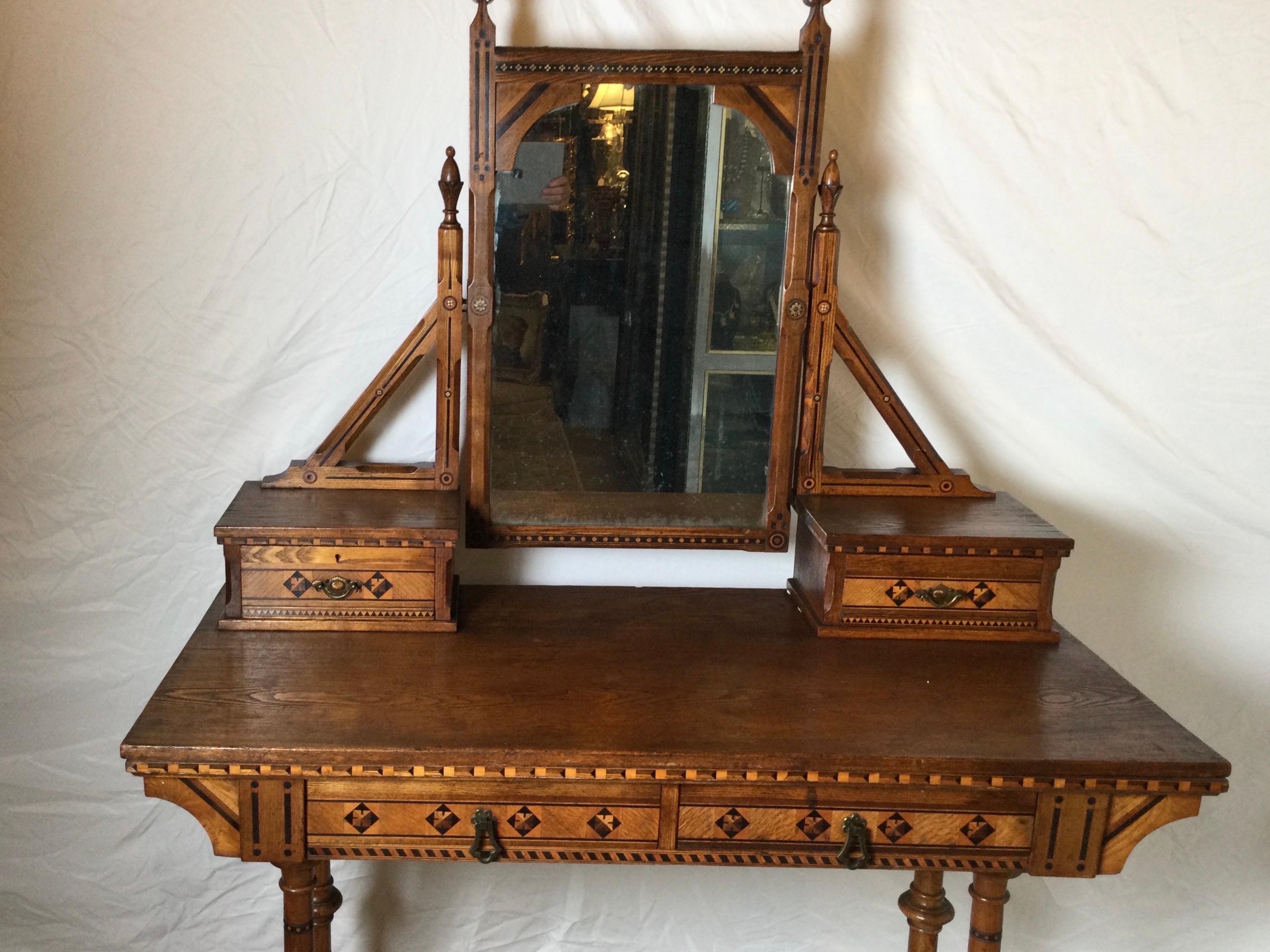 Aesthetic movement with a gothic influence Vanity dressing table in walnut with inlays of kings wood and tulip wood. The top mirror with arch above the 2 jewelry drawers with a rectangular surface with two drawers along the apron. Retaining original