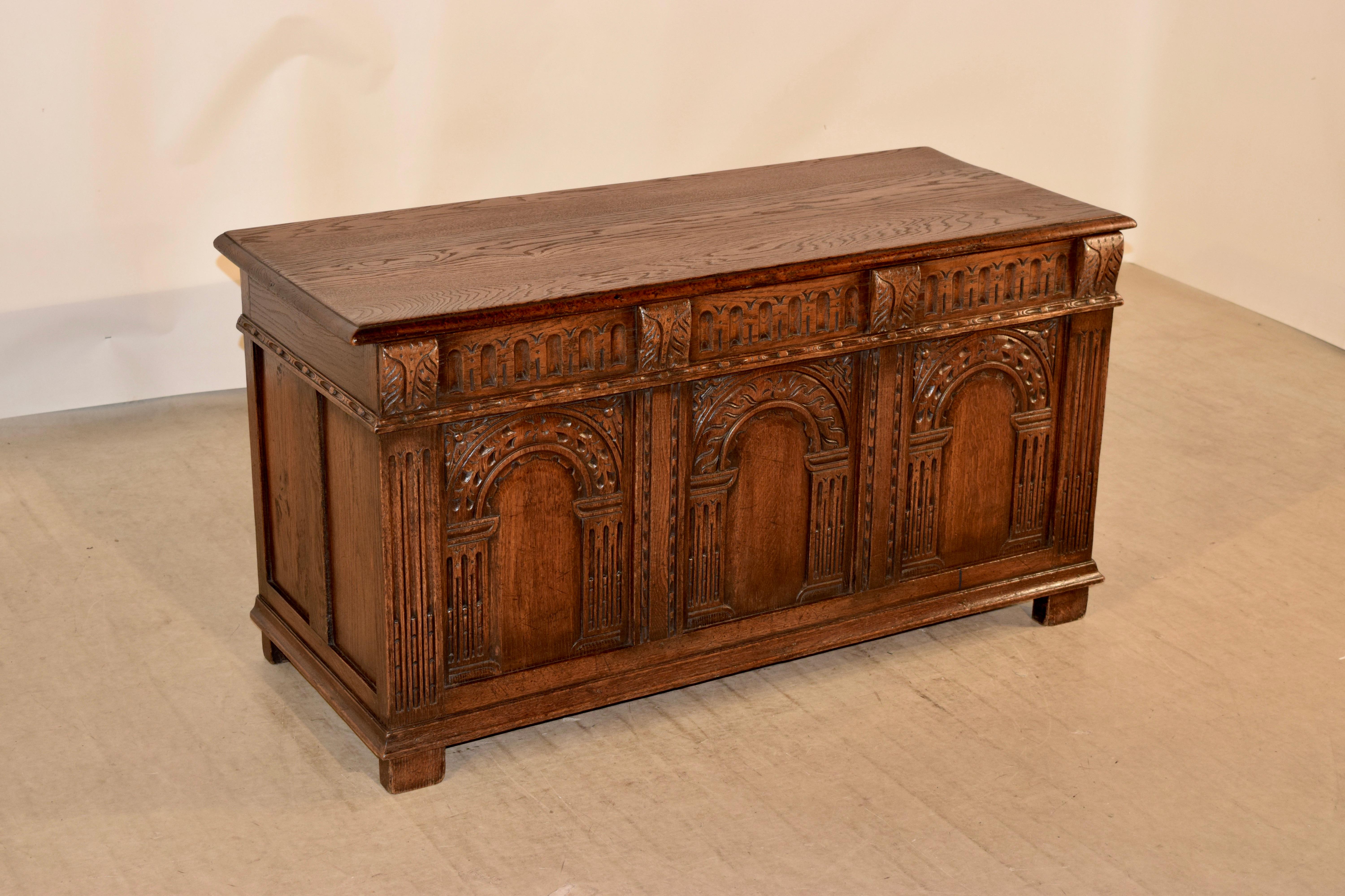 19th century oak blanket chest from England with a beveled edge around the top, which opens to reveal storage. The sides are paneled and have hand carved decorated molding. The front is paneled as well and has hand carved decorative carvings over