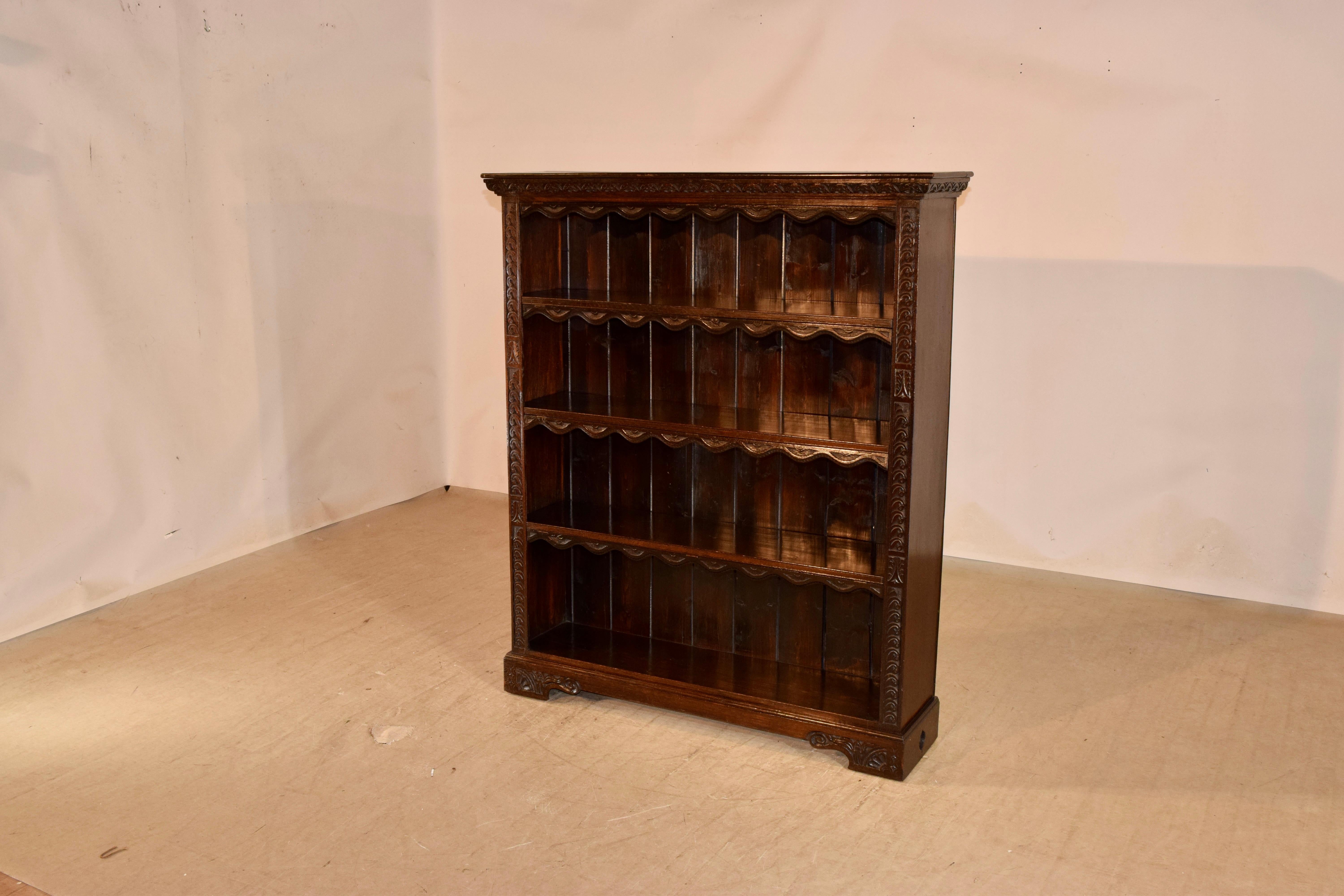 19th Century oak bookcase from England with a hand carved decorated frame and three shelves, all with very unusual carved wooden dust flaps that are hinged for lifting to access taller books. The sides are simple and the case is resting on lovely