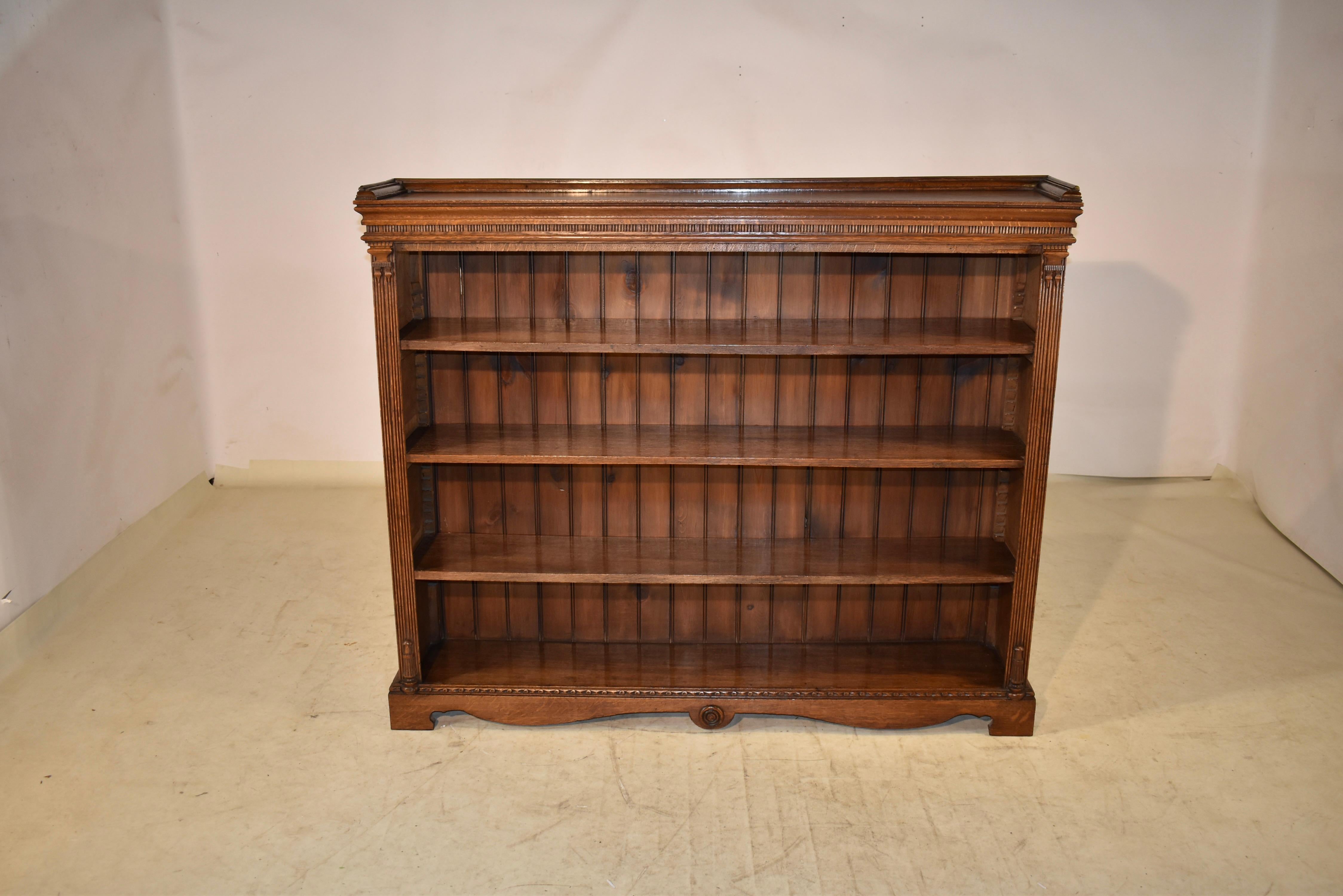 19th Century oak bookcase from England with a molded gallery around the back for additional shelving space. This is over a crown molding with a dentil type carved border. The bookcase has four moveable shelves, flanked by reeded columns which have