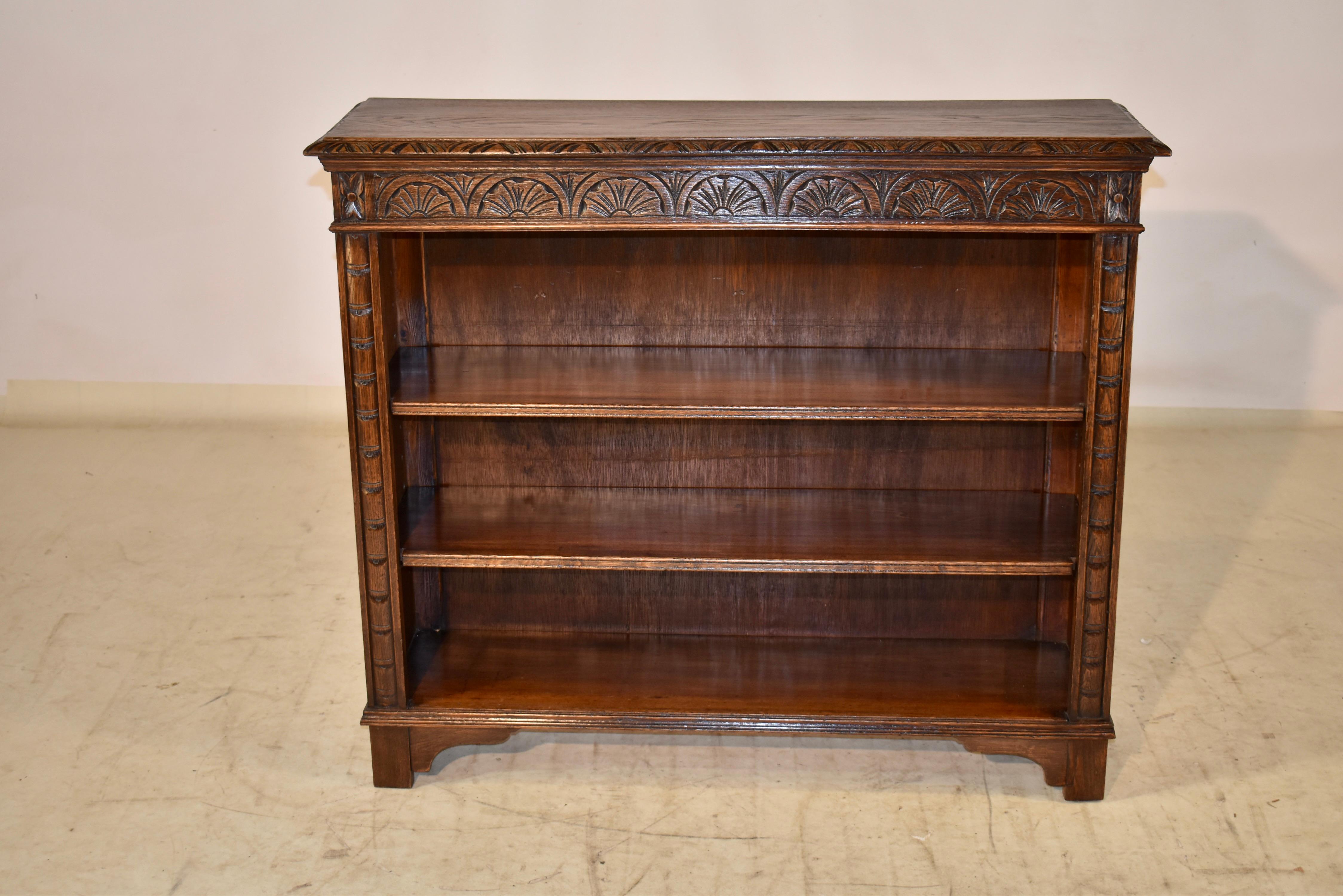 19th century hand carved oak bookcase with a beveled and hand carved decorated edge around the top, following down to a molded edge over simple sides and three shelves in the front of the case, two of which are adjustable. The shelves are surrounded