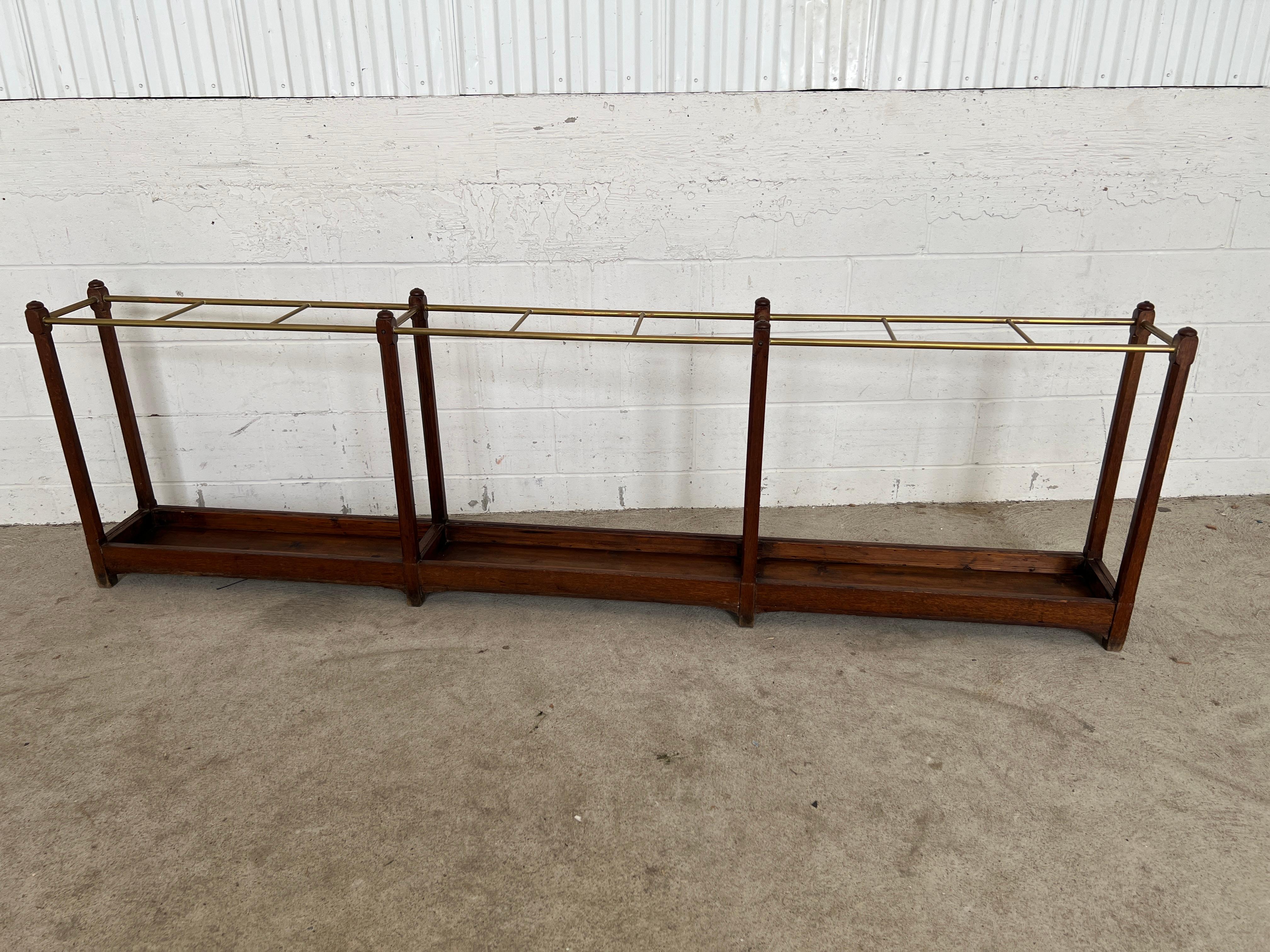 English, 19th century.

A highly unusual and likely custom made for a high-end Victorian hotel, this 8FT long cane or umbrella stand is constructed with an oak frame in three main sections. The body has brass poles to separate the sections for