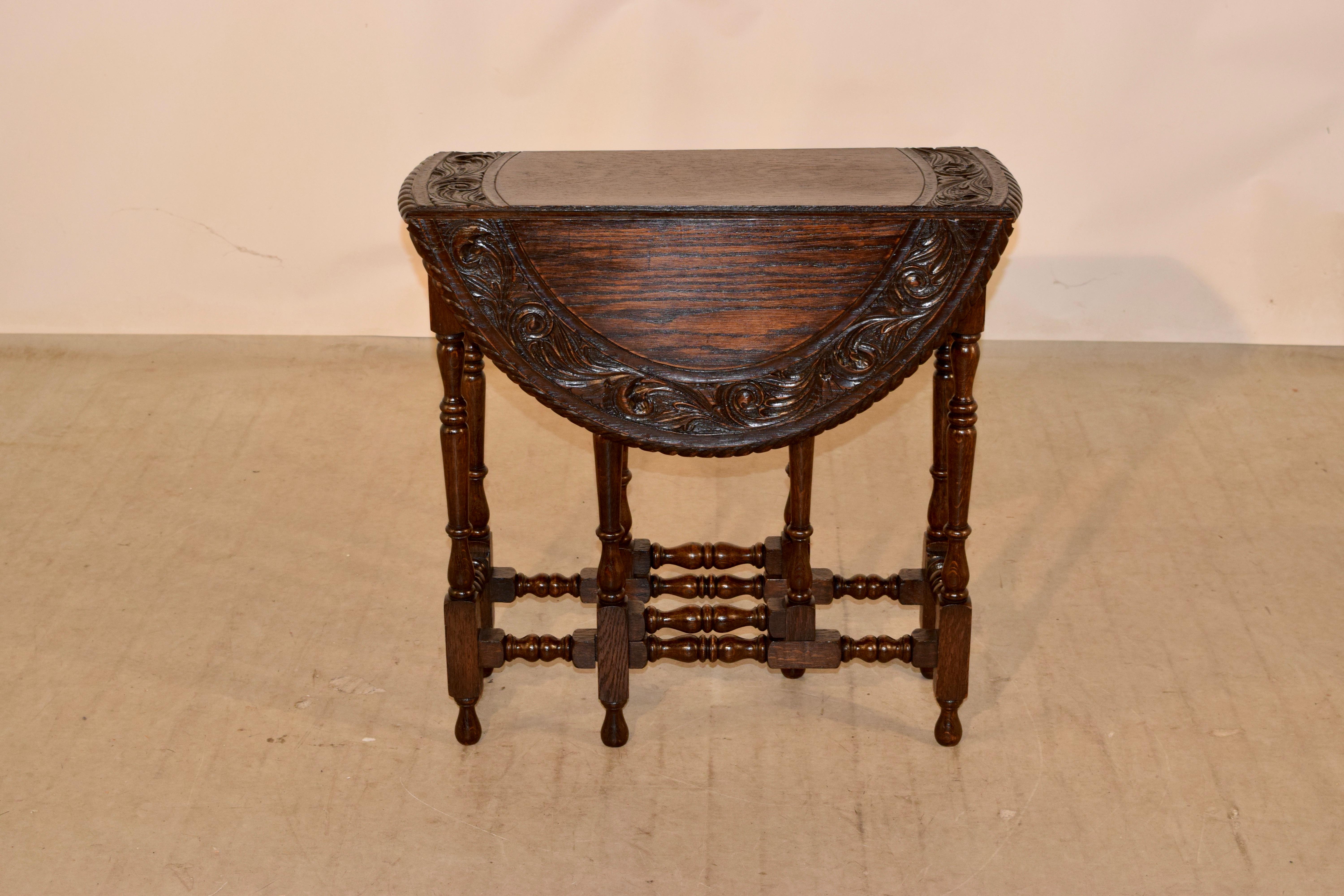 19th century oak gate leg from England with a carved and beveled edge surrounding the carved banded top. The apron is scalloped on the ends and the table is supported on hand turned legs, joined by turned stretchers and raised on hand turned feet.