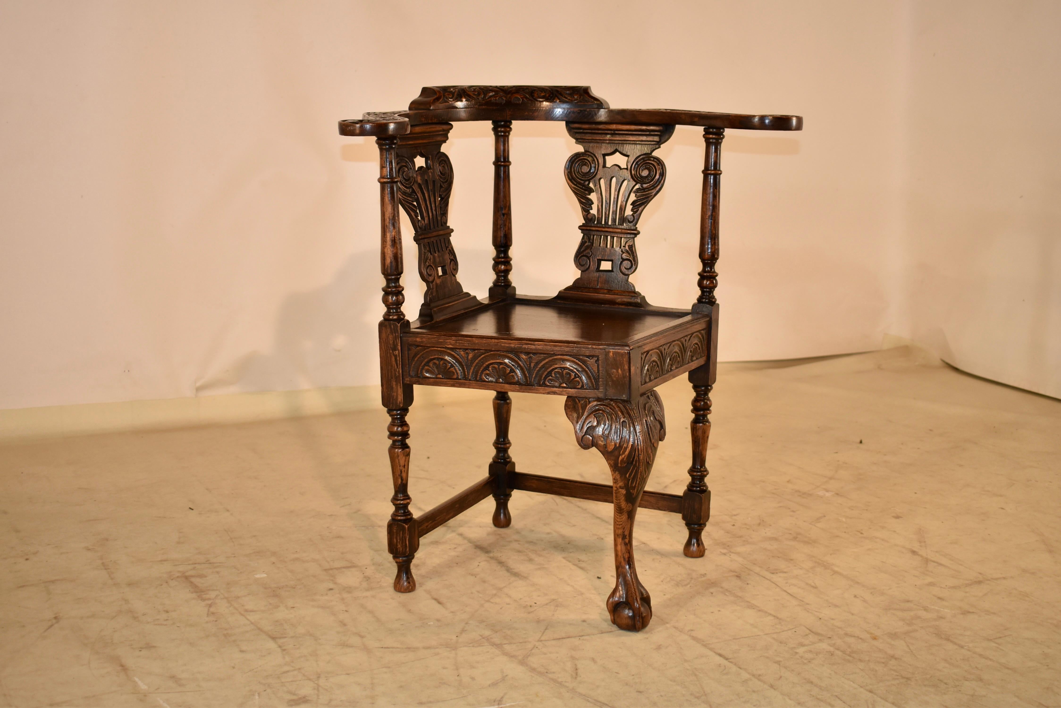 19th century oak corner chair from England.  The arms and back of the chair are wonderfully barrel shaped and embellished with hand carved decorations.  The top rail of the chair is supported on hand turned supports, and there are two pierced and