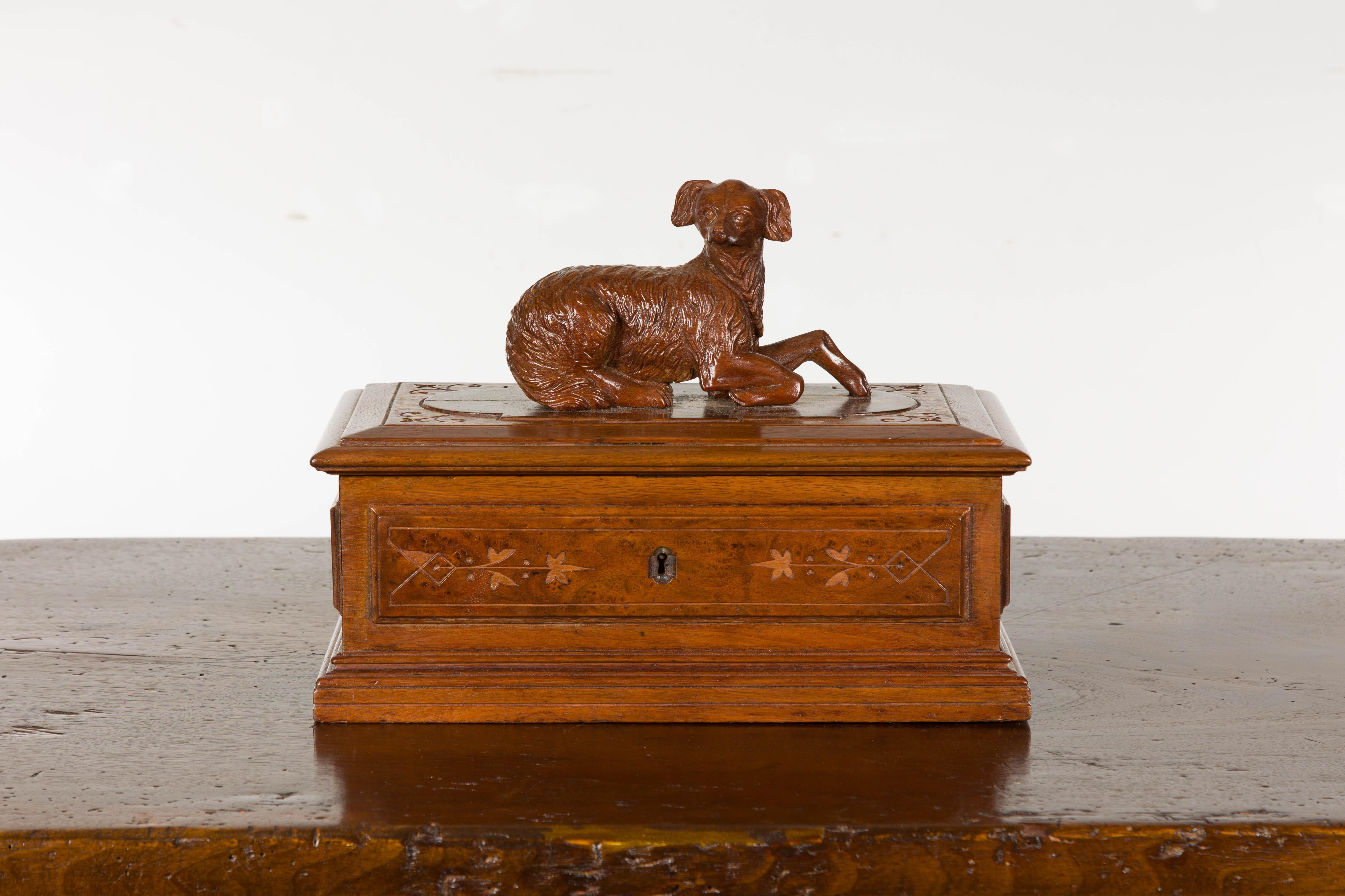 An English oak decorative box from the 19th century with carved dog on the lid, stylized foliage on the front and partitioned interior. Immerse yourself in the delicate craftsmanship of this 19th-century English oak decorative box, a piece that