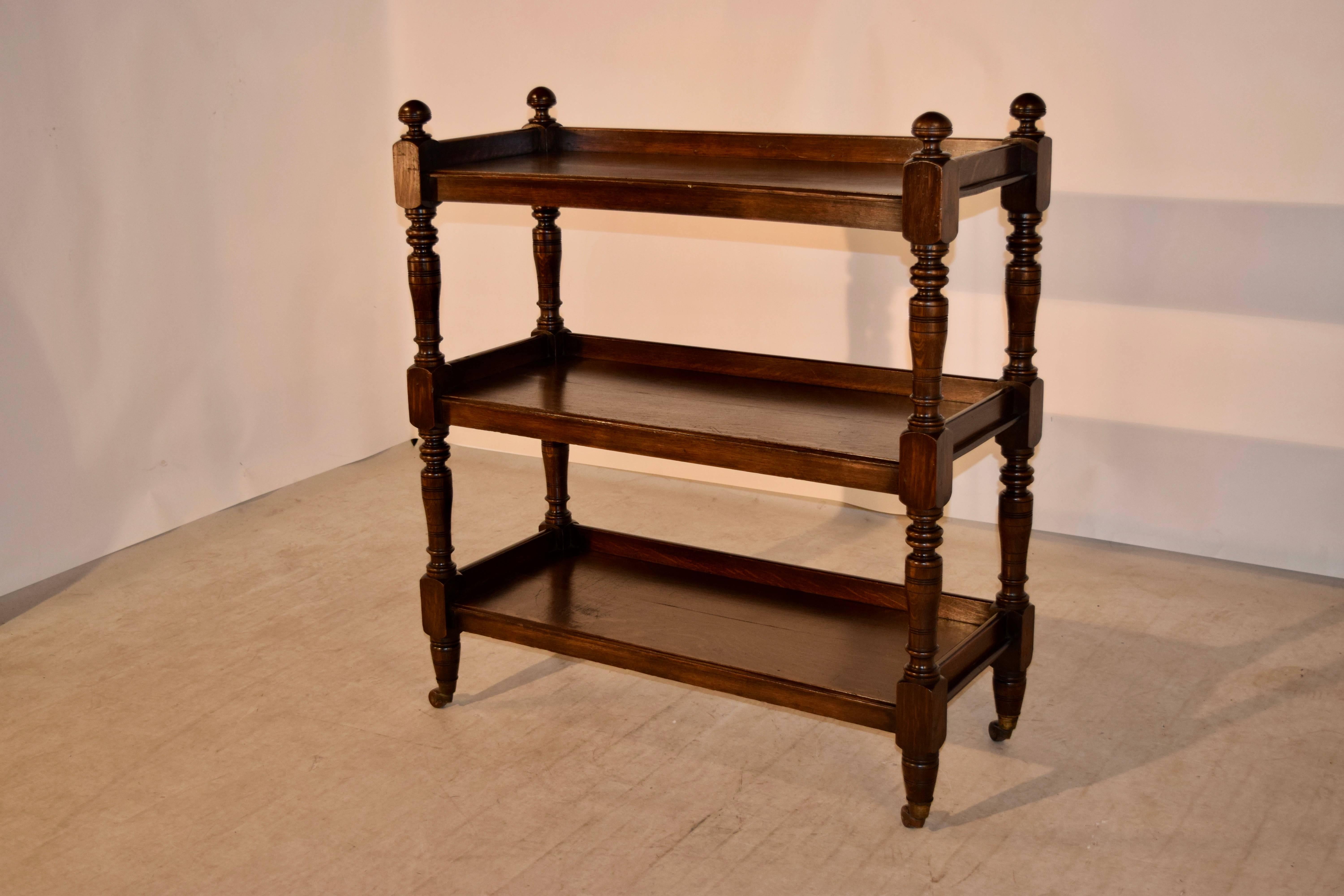 19th Century English oak dessert buffet with three shelves, decorated with hand-turned finials at the top and hand-turned shelf supports. All three shelves are surrounded by galleries, and the piece is resting on original casters.