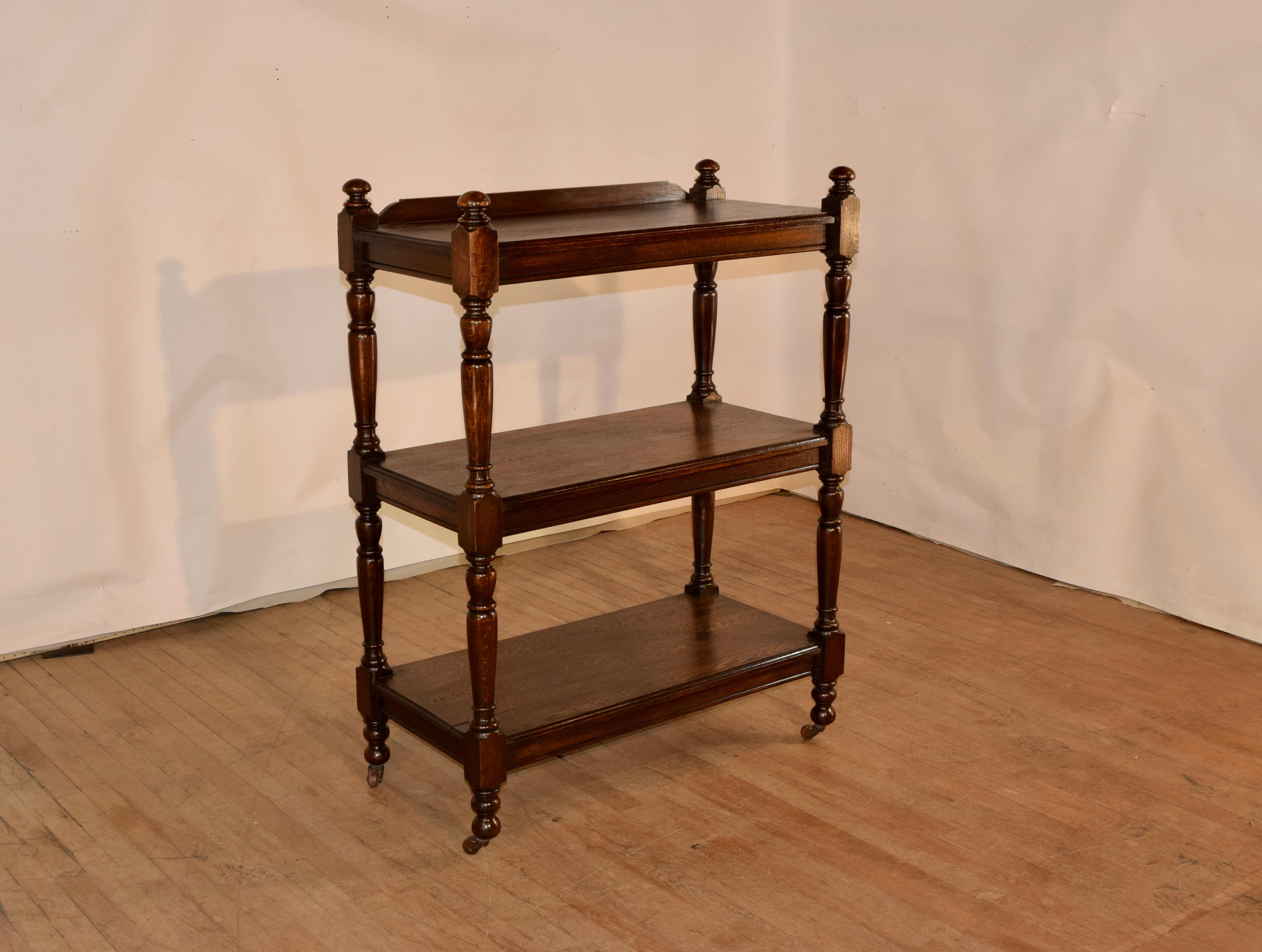 19th century oak dessert buffet from England with a shaped backsplash on the top and three shelves.  The legs are hand turned and also serve as the shelf supports.  They are adorned with hand turned finials at the top and retain what appear to be