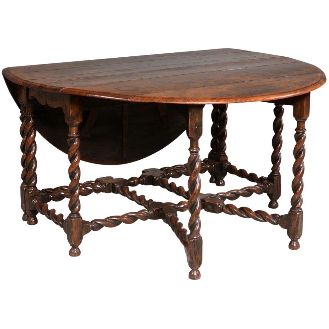 Circa 1860 England.

A gorgeous oak folding double gateleg table, filled with old-world charm. The thick tabletop is supported by barley twist table legs and stretchers and scrolling aprons on both ends. The gatelegs are joined to the stretchers