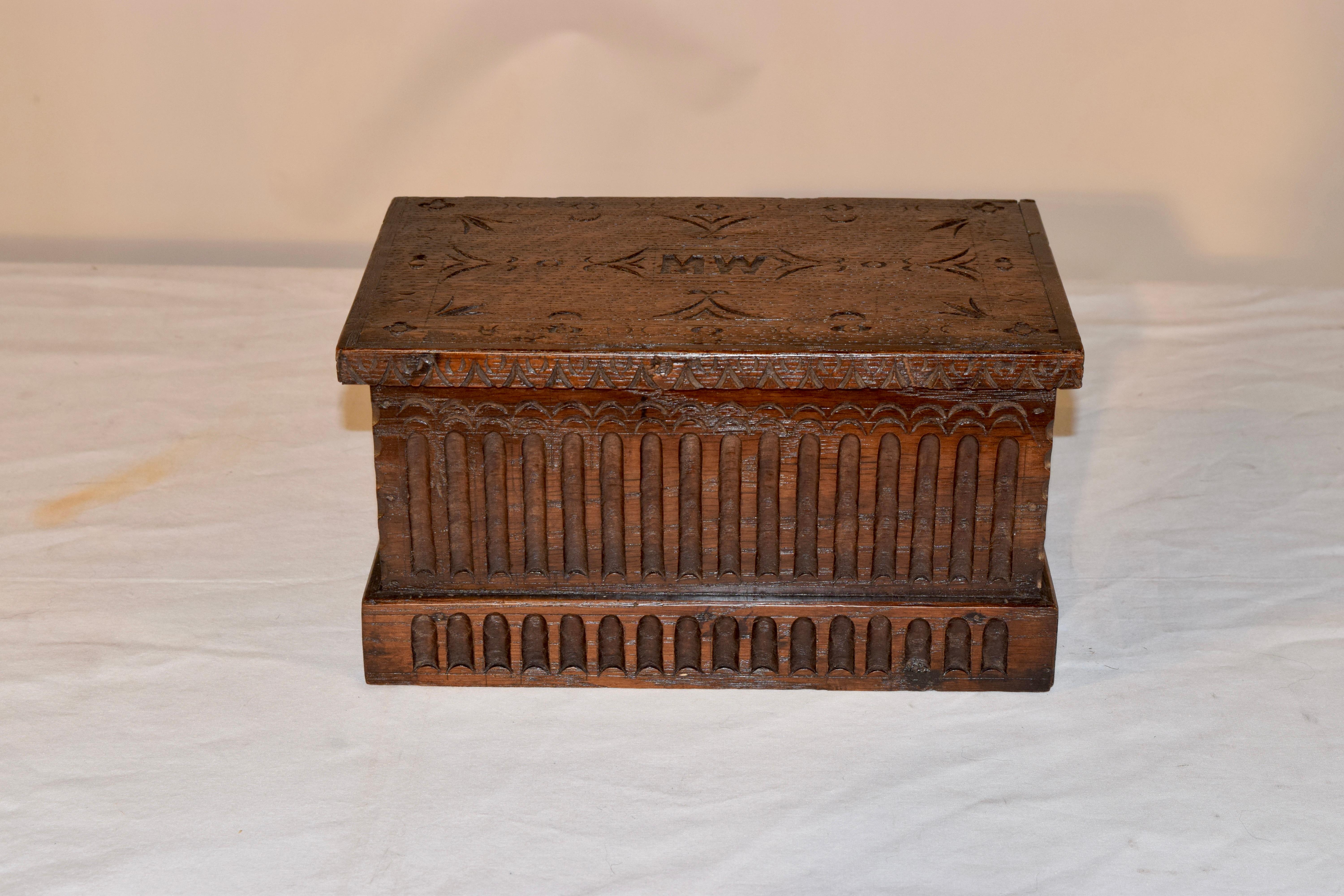 19th century oak box from England with lovely carving throughout. The box is reminiscent of a miniature blanket chest with the initials MW carved into the lid. The top opens to reveal generous storage. The sides and front have lovely nulling