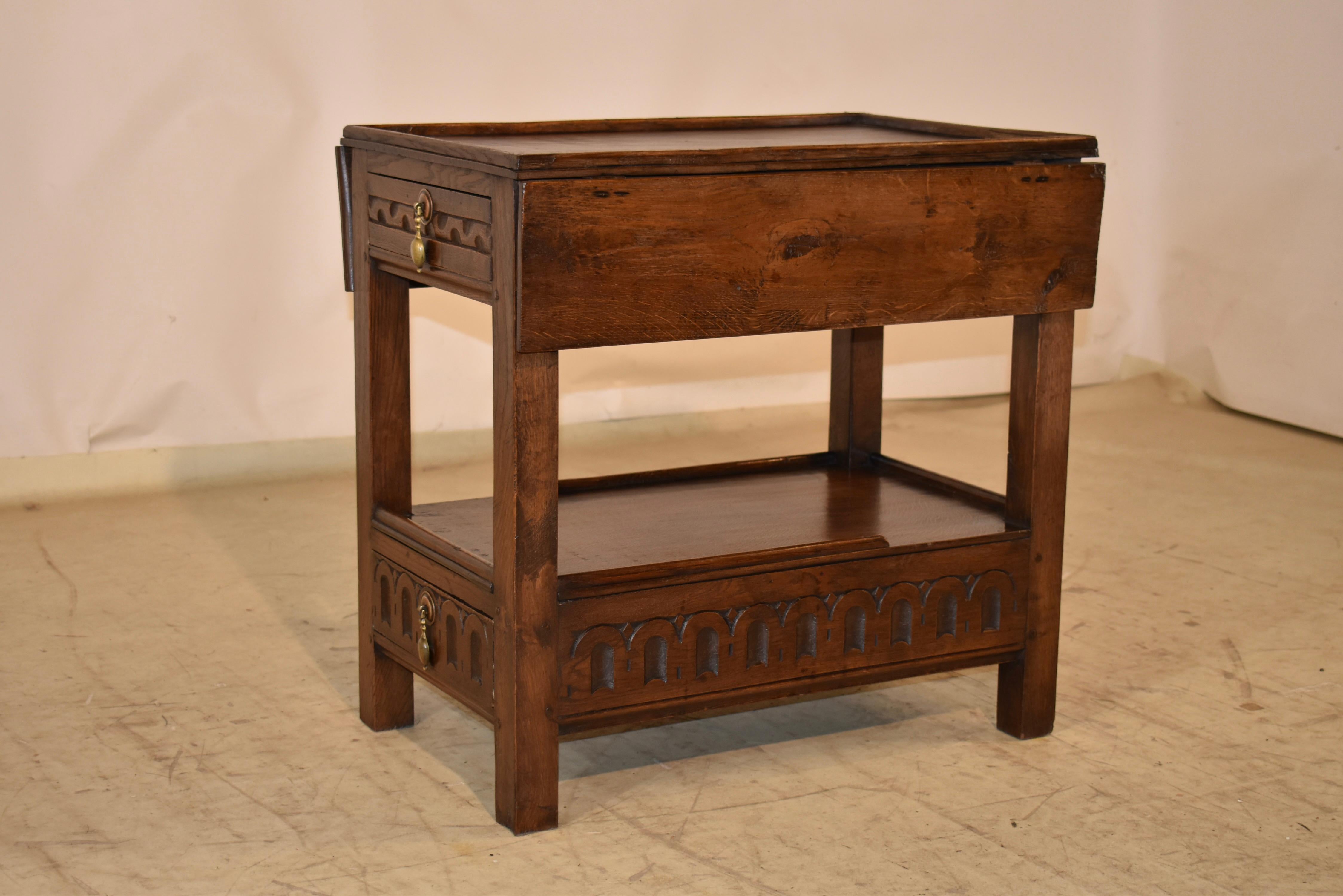 19th century oak side table with drop leaves from England.  The top has a small molded rim around the top and has two drop leaves, which, when extended, the top measures 29.88 inches wide.  There is a single drawer with a hand carved central panel,