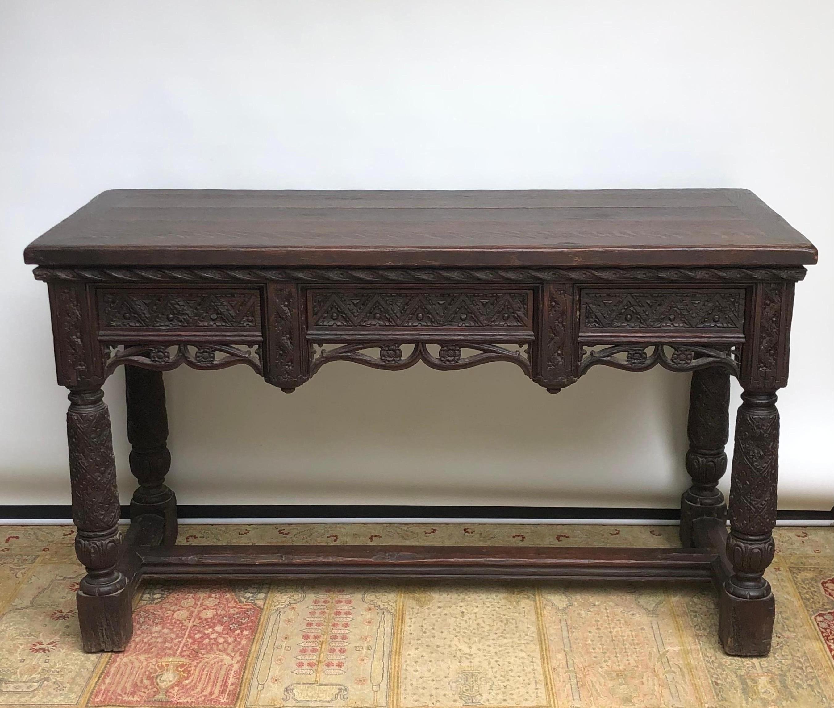 A elegant Elizabethan Style Oak hand carved Console Hall Table in the Gothic taste, made in England during the Renaissance Revival Period. The Renaissance Revival Sideboard is wonderfully proportioned and is handmade with solid English oak. The