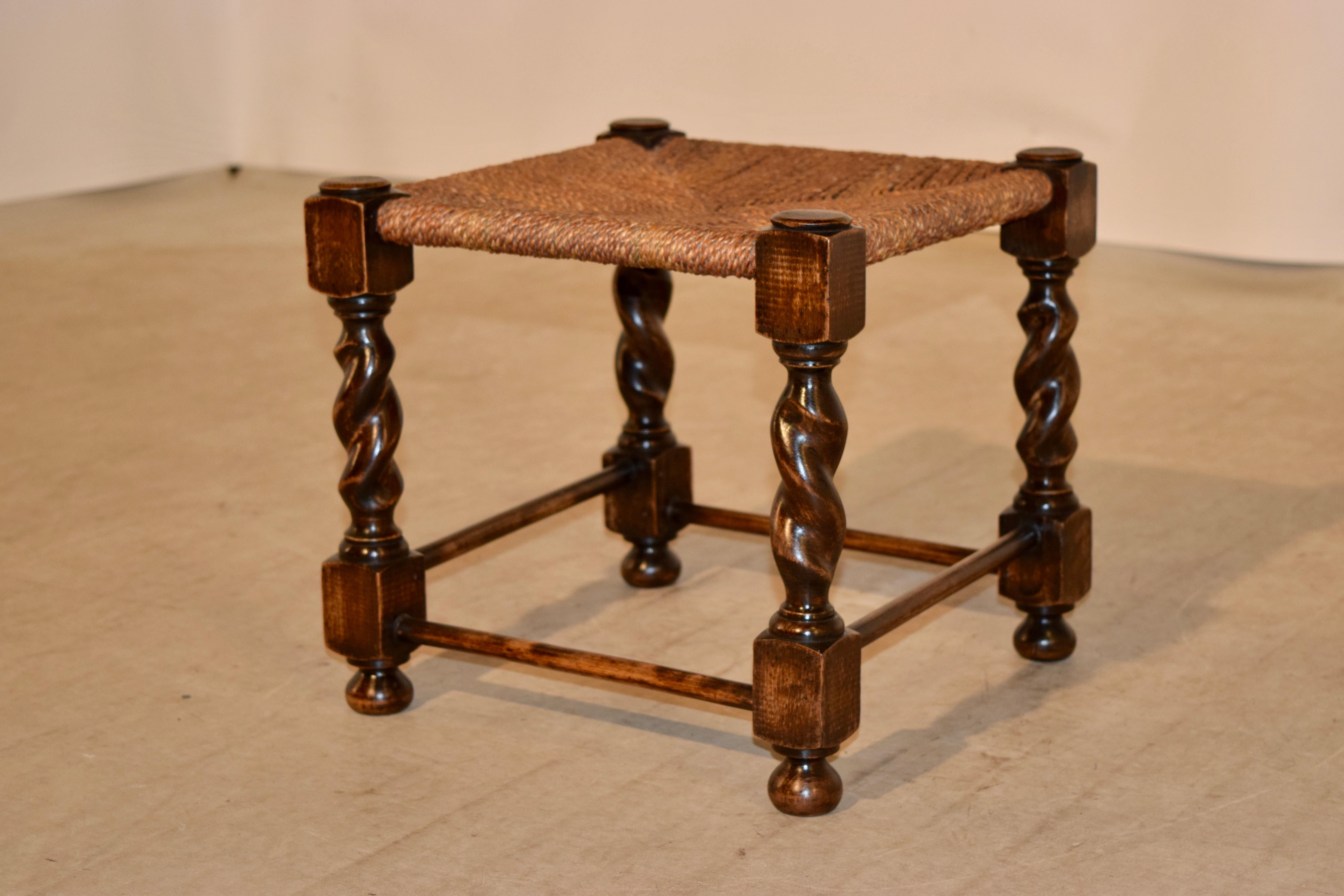 19th century English oak foot stool with hand-turned barley twist legs joined by simple stretchers and hand-turned feet. The top is handwoven rush.