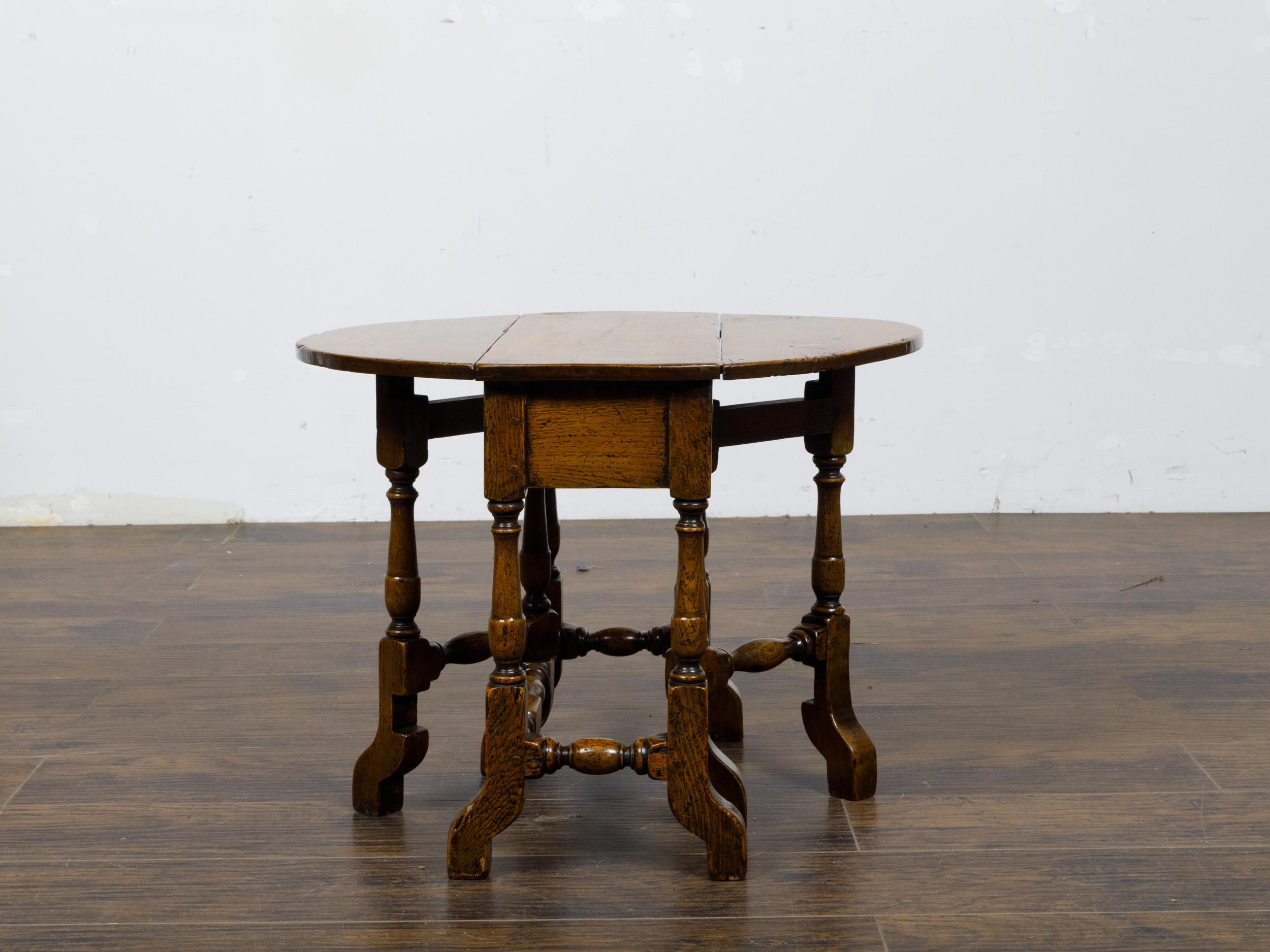 This petite 19th-century English oak gateleg table combines traditional craftsmanship with charming versatility, making it a timeless addition to any home. Crafted from solid oak, the table features a rich patina that highlights its age and the