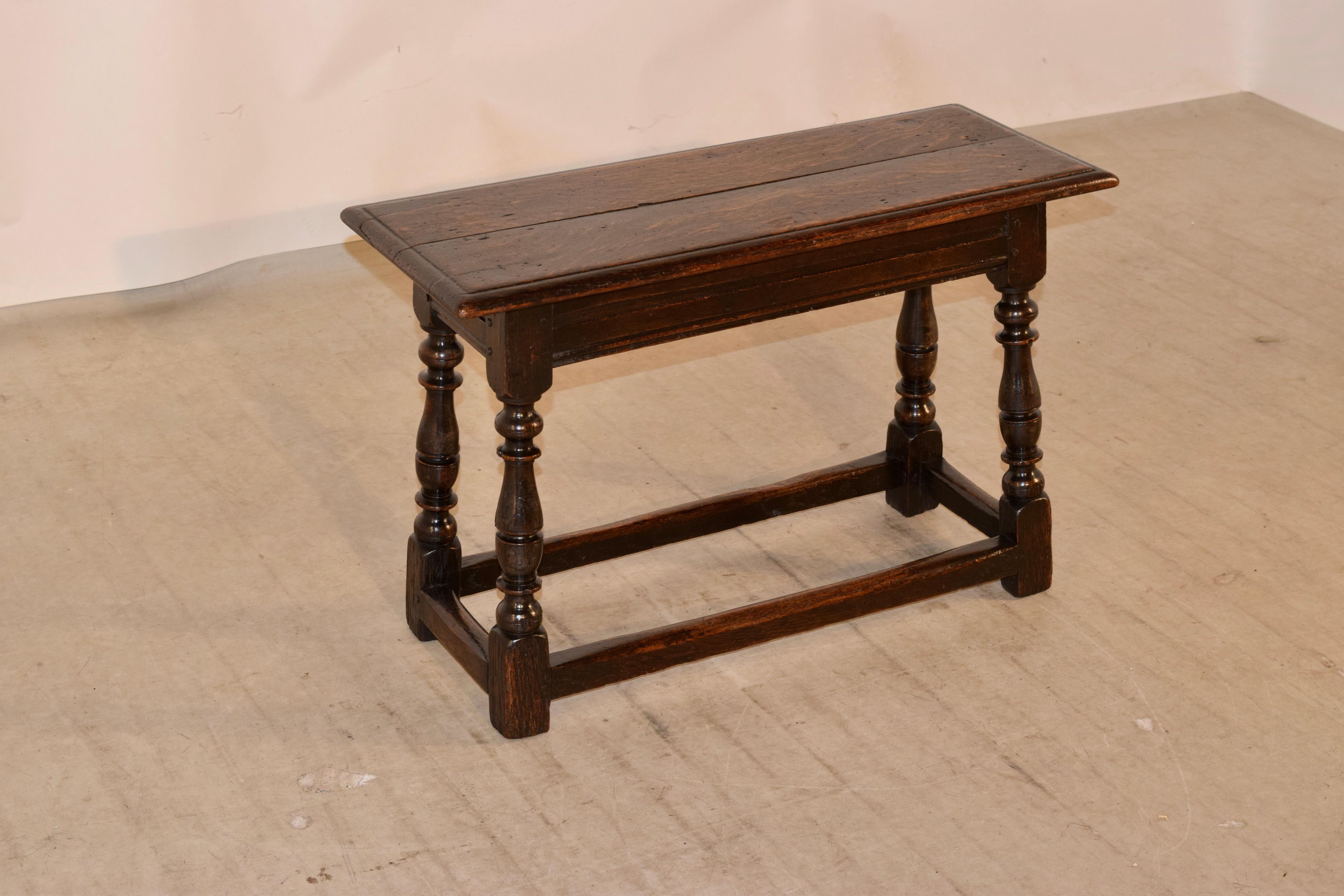 19th century oak joint bench from England with a two plank top which has a beveled edge and follows down to a simple apron with routed decoration. The piece is supported on hand-turned and splayed legs joined by simple stretchers.