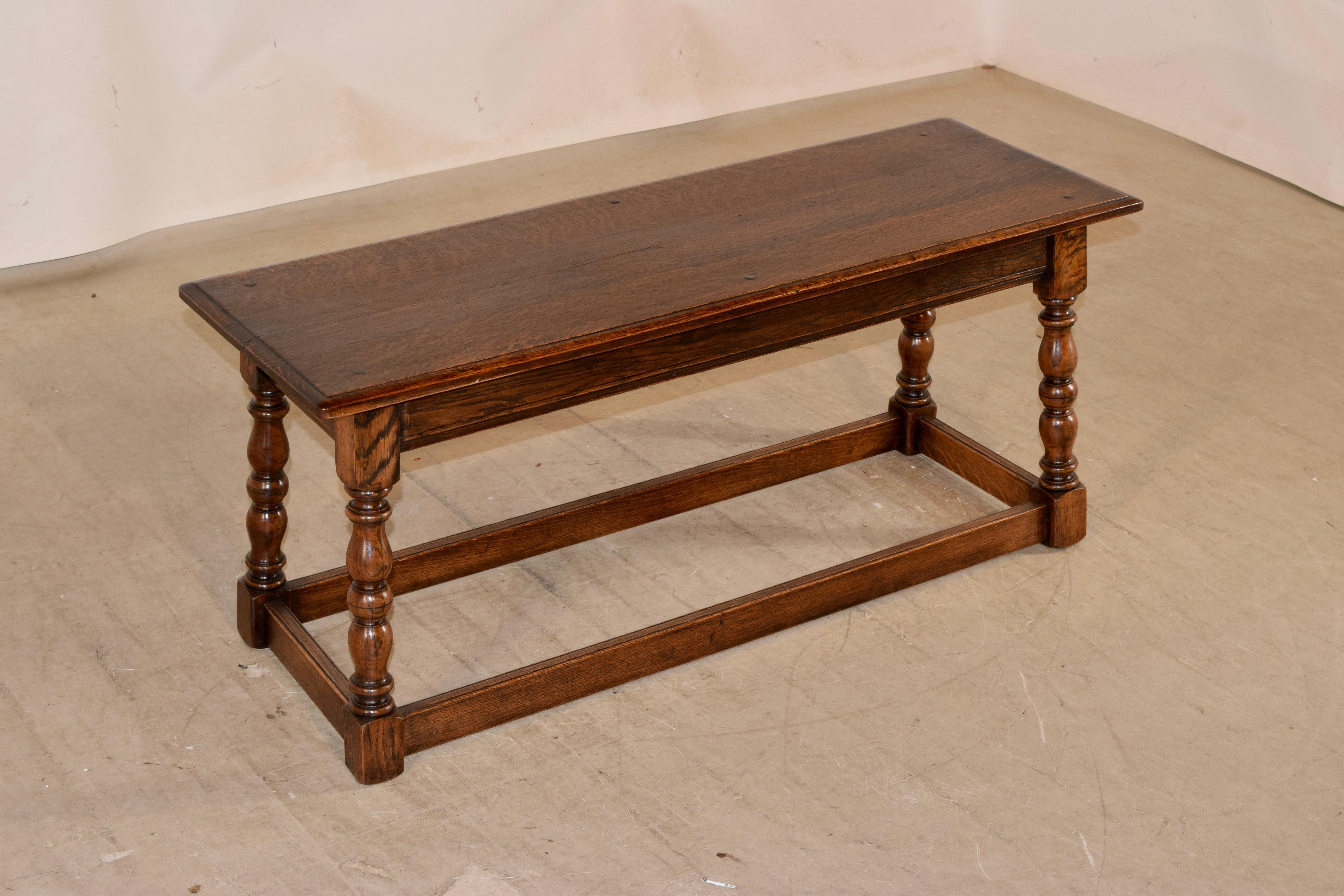 19th century oak joint bench from England with a beveled edge around the top, following down to a simple apron. The piece is supported on hand turned splayed legs, joined by simple stretchers.