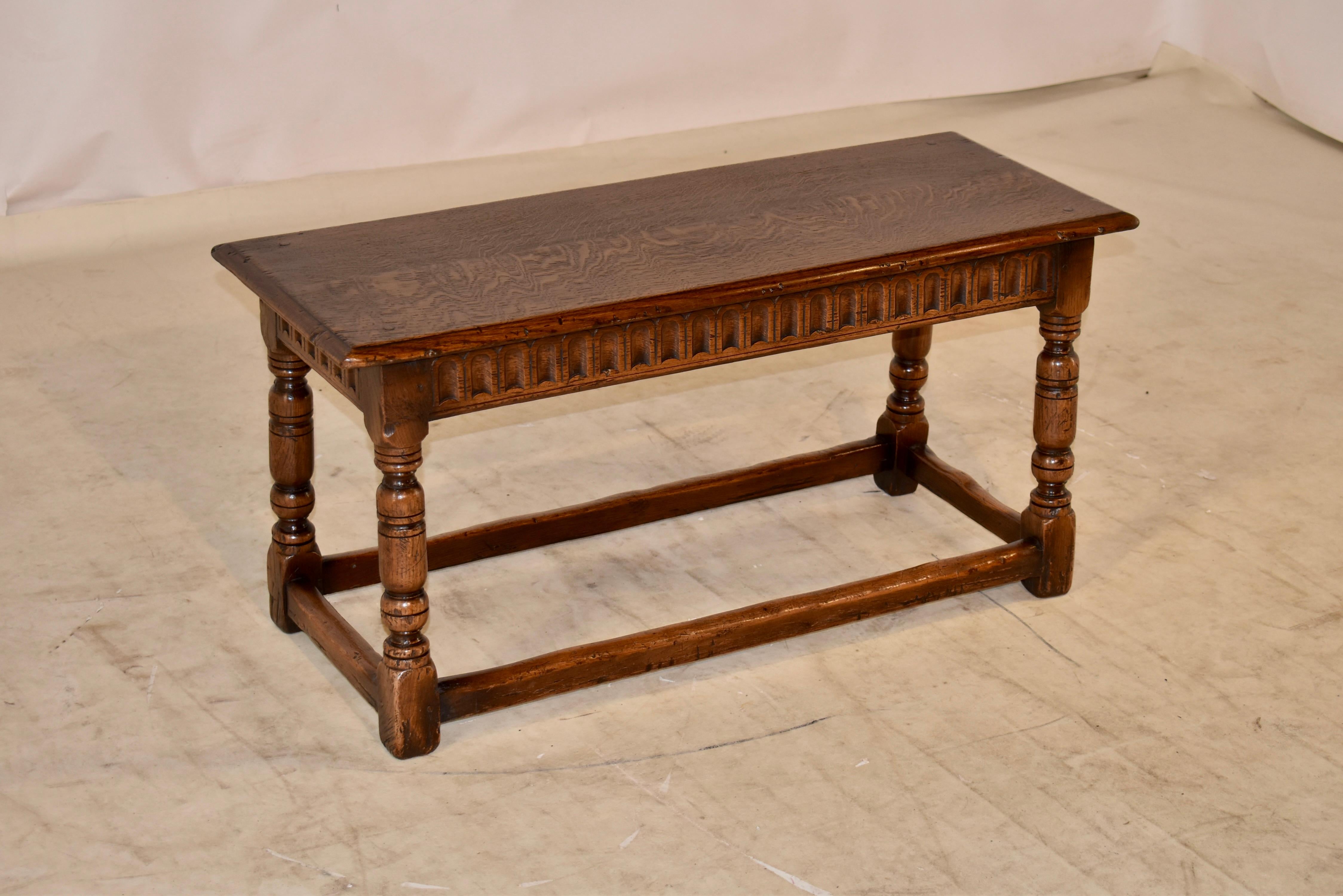 19th century oak joint bench from England with a two plank top which has a beveled edge over a lovely hand carved apron. the piece is supported on hand turned legs, joined by simple stretchers. Lovely piece in a wonderful size.
