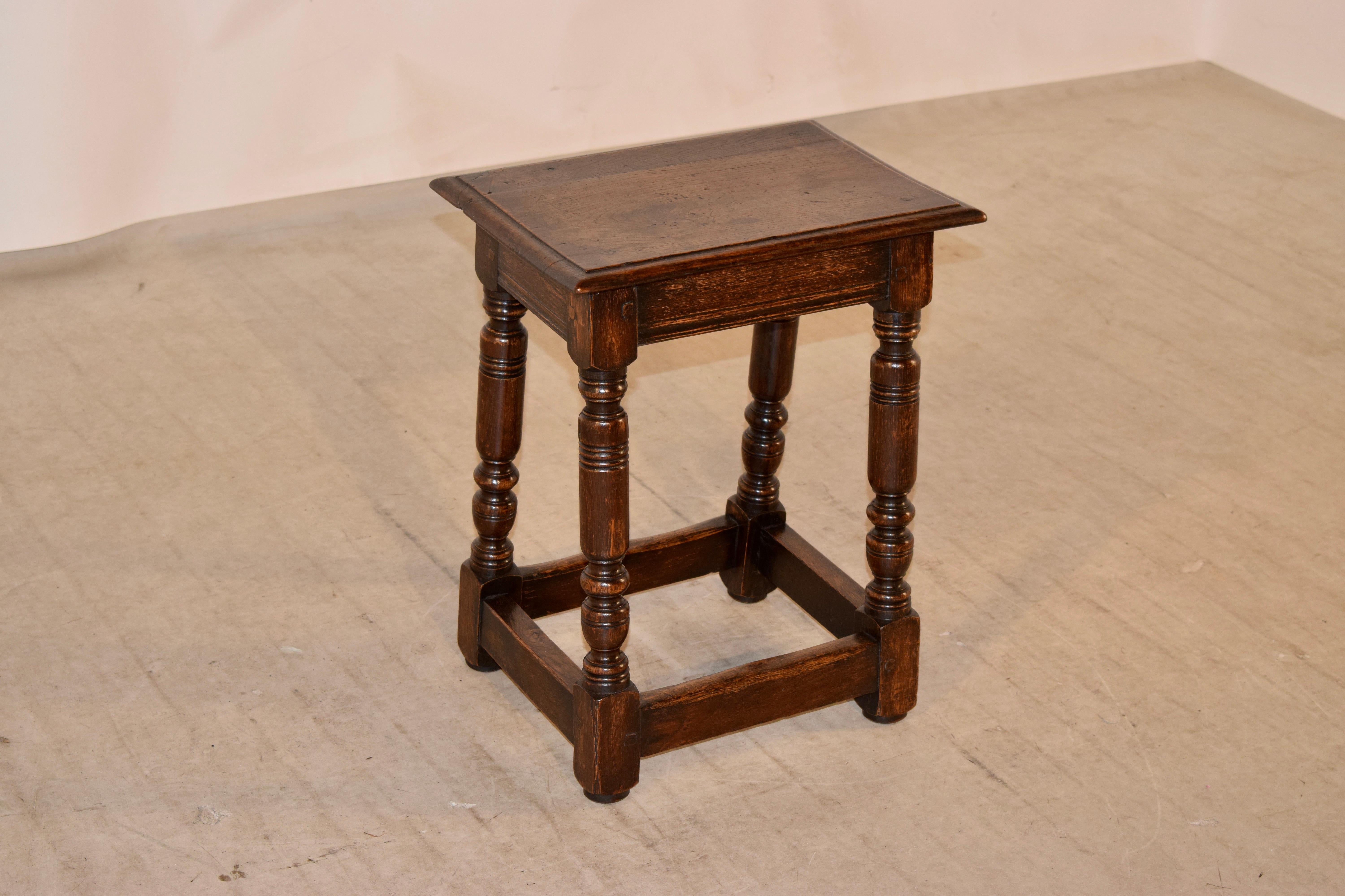 19th century English oak joint stool with a beveled edge around the top following down to a simple apron and nicely hand-turned legs, which are slightly splayed and are joined by simple stretchers.