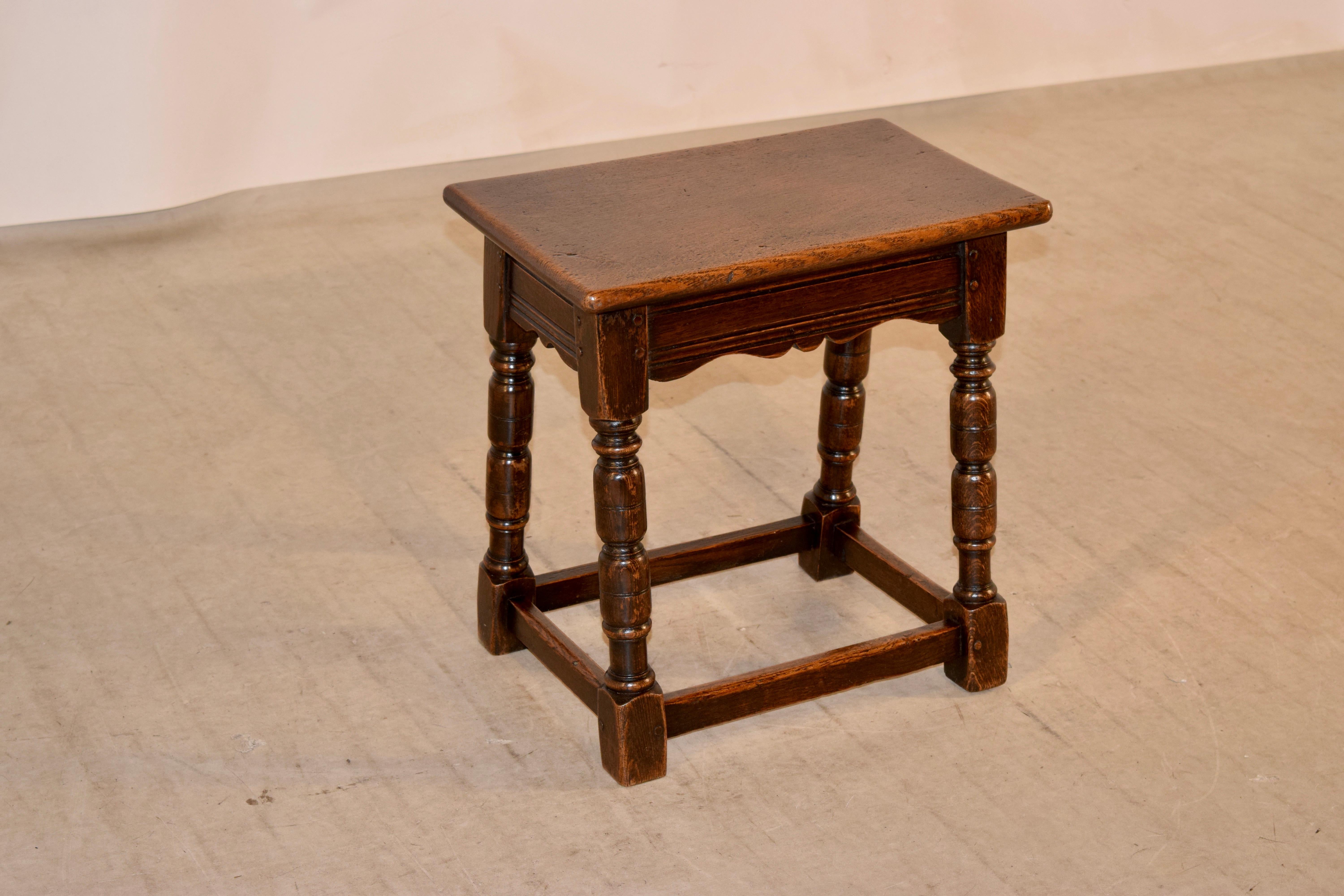 19th century English oak joint stool with a simple top following down to hand scalloped aprons with routed decoration and supports on splayed hand turned legs, joined by simple stretchers.