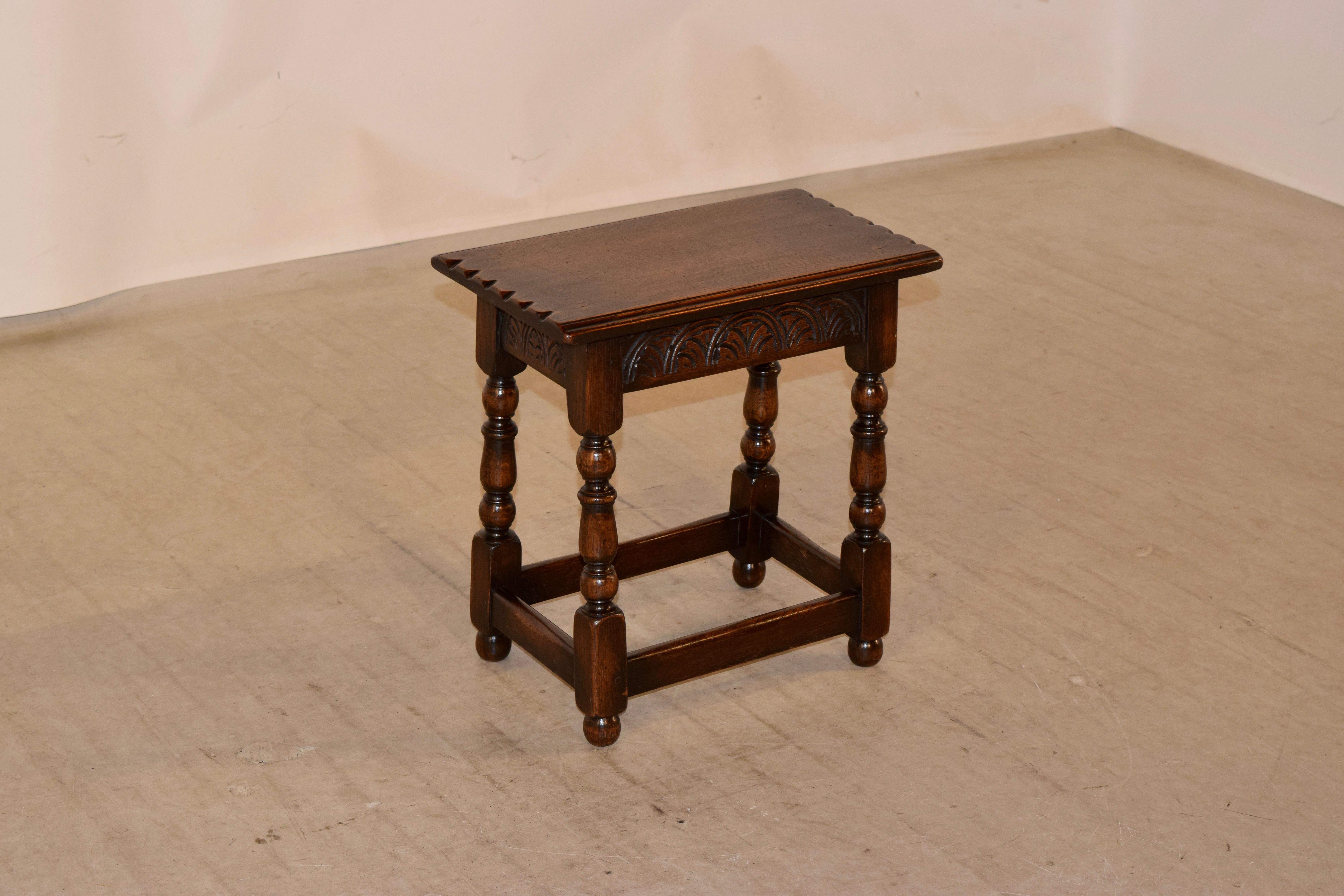 Late 19th century oak joint stool from England. The top has routed and pie crust edges, following down to hand carved decorated aprons and hand turned legs, joined by simple stretchers.