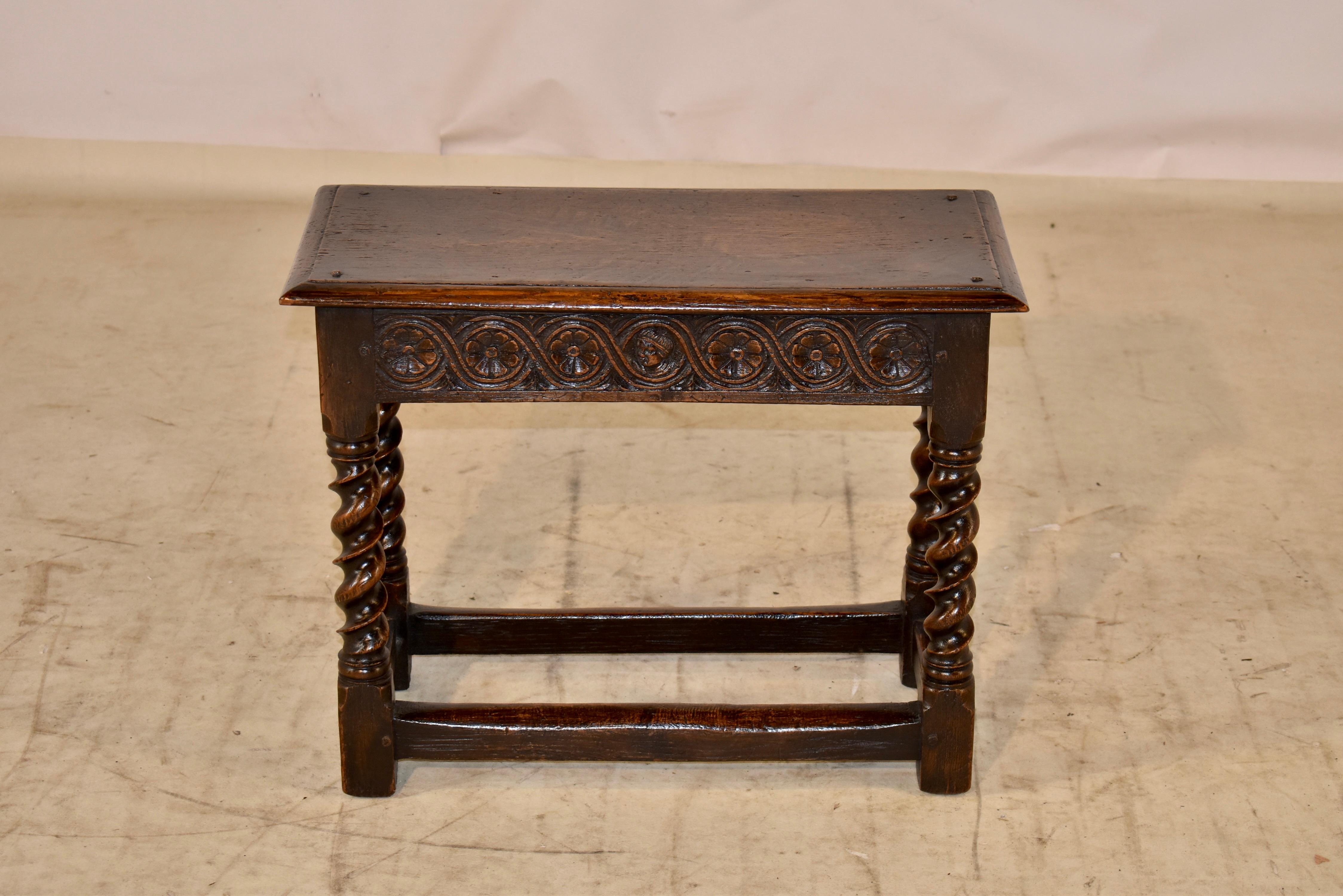 19th century oak joint stool from England with a beveled edge around the single plank seat, which also has pegged construction. The apron is hand carved decorated on all four sides for easy placement in any room. The stool is supported on hand