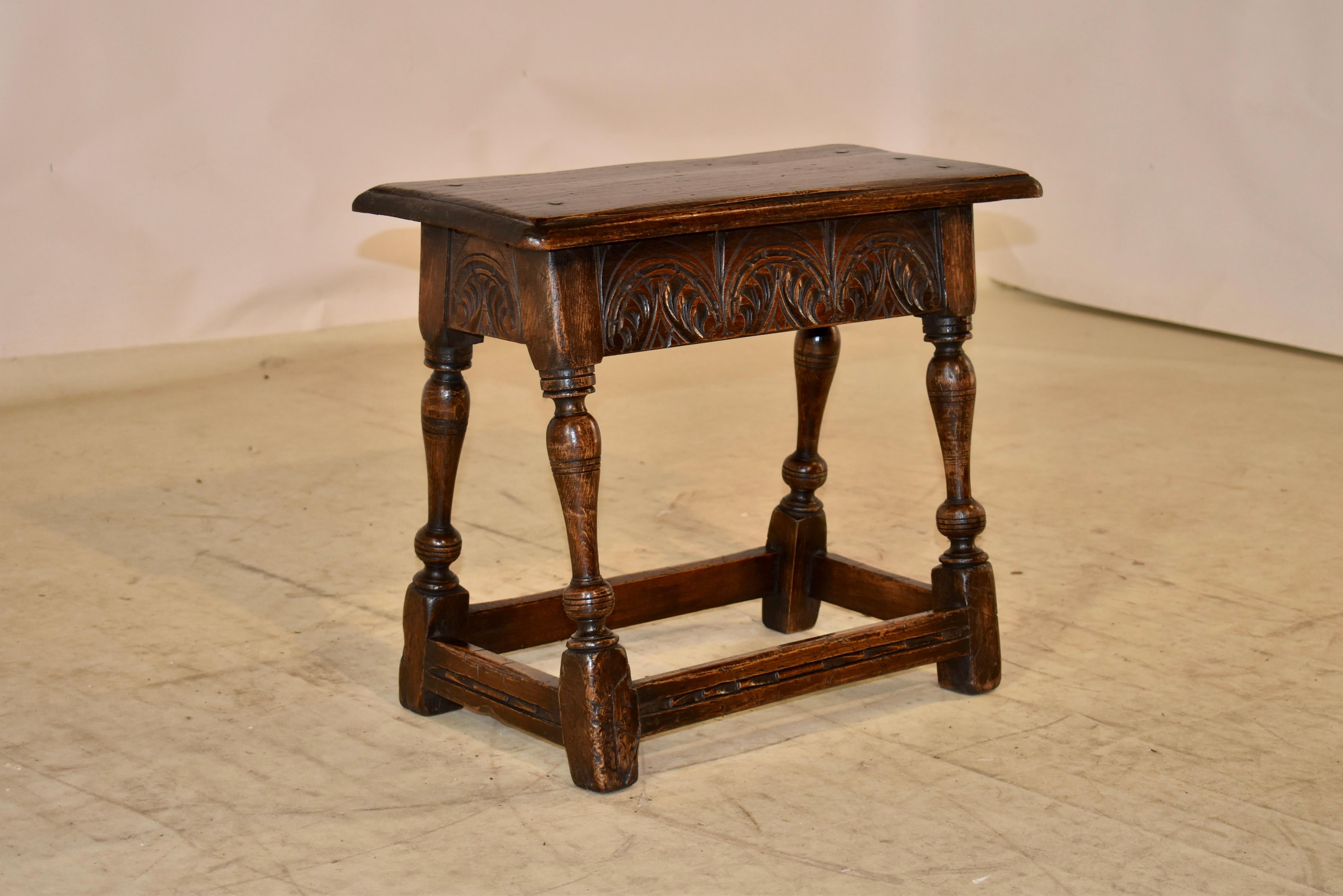 19th century Oak joint stool from England with a beveled edge around the top, which is also chamfered and of pegged construction. The apron is wonderfully hand carved on all four sides for easy placement in any room. The stool is supported on hand