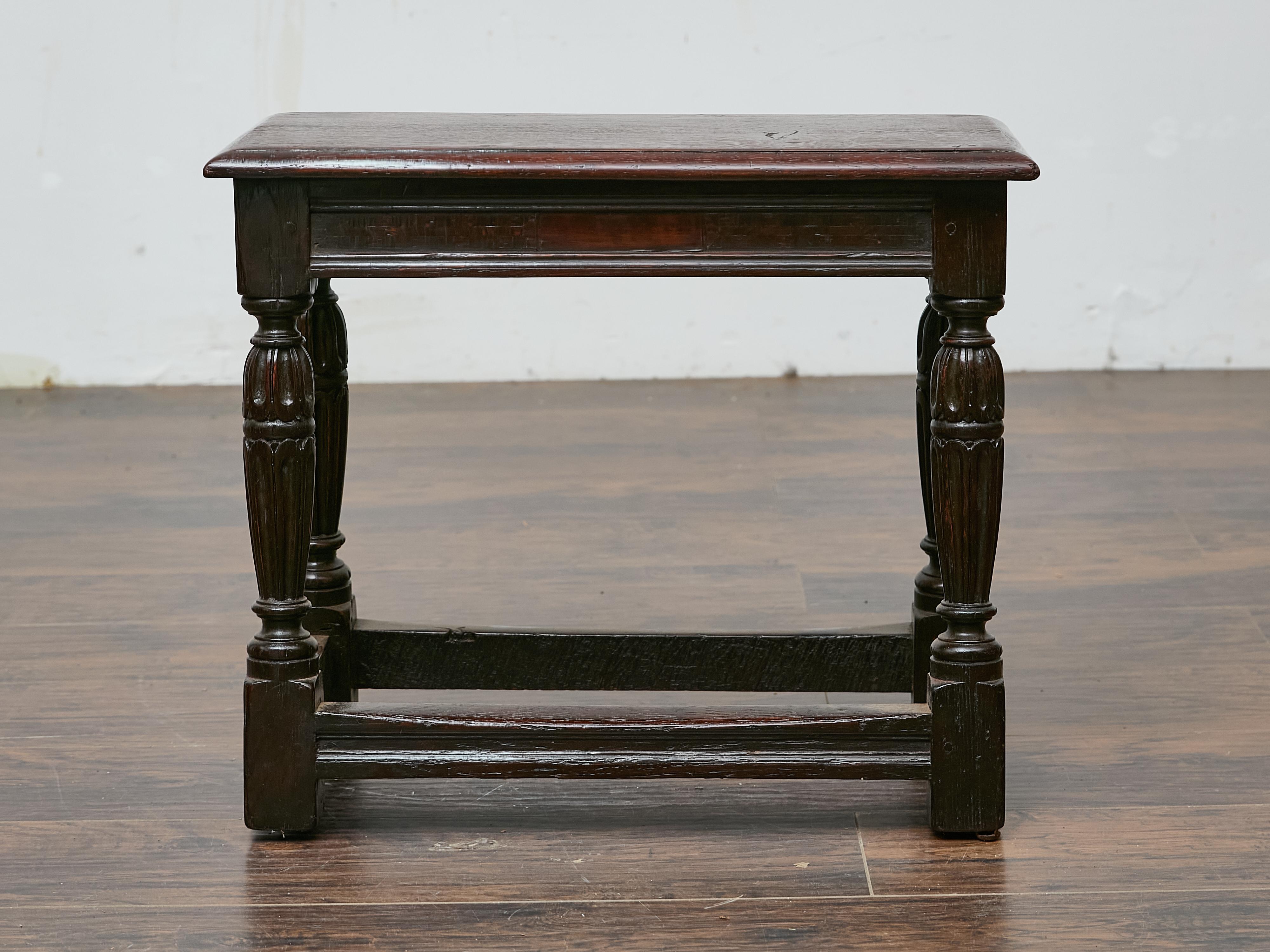 Tabouret en chêne anglais datant du XIXe siècle, fabriqué dans le style traditionnel des exemples antérieurs du XVIIe siècle. Cette pièce solide et bien proportionnée présente un plateau rectangulaire aux bords adoucis, reposant sur un tablier